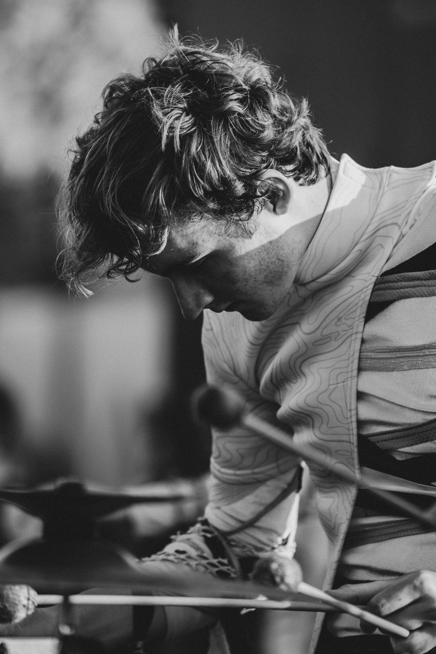 Black and white photo of a curly-haired musician playing xylophone with mallets, focused and intense.