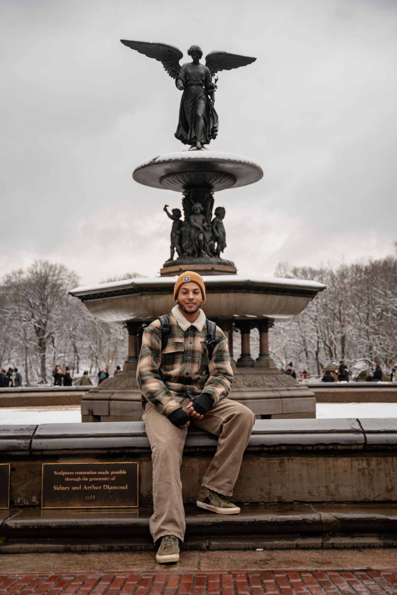 Black and white photo series of someone sitting on the edge of Bethesda Fountain in Central Park during winter.