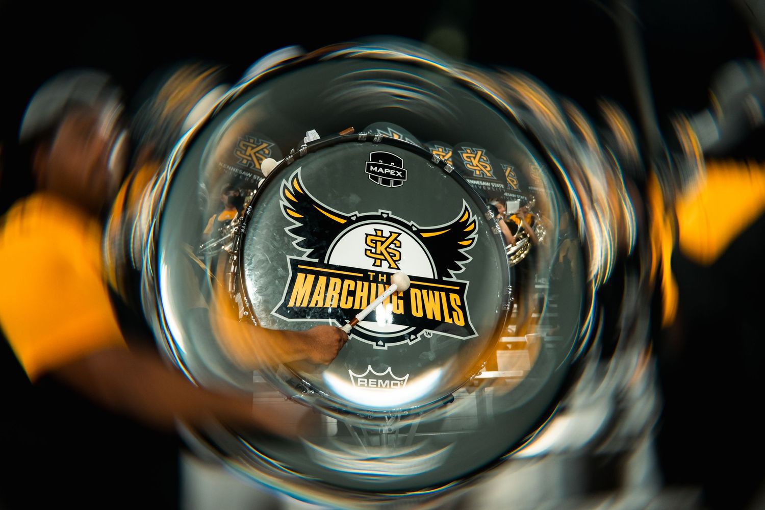 Swirling motion blur effect captures marching band performance with orange and black color tones.