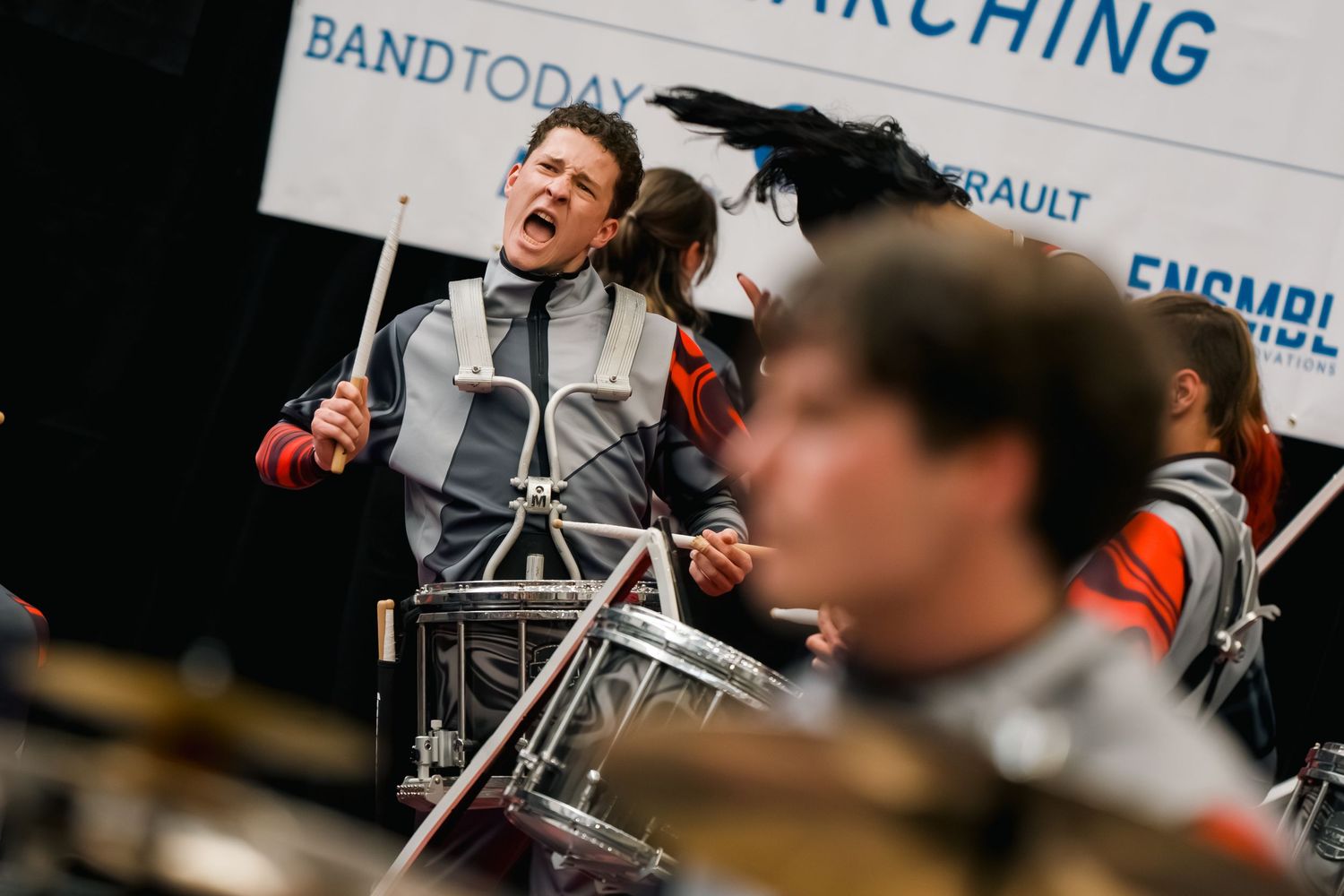 Passionate drummer performs at a marching band competition, playing with intensity at an indoor percussion event.