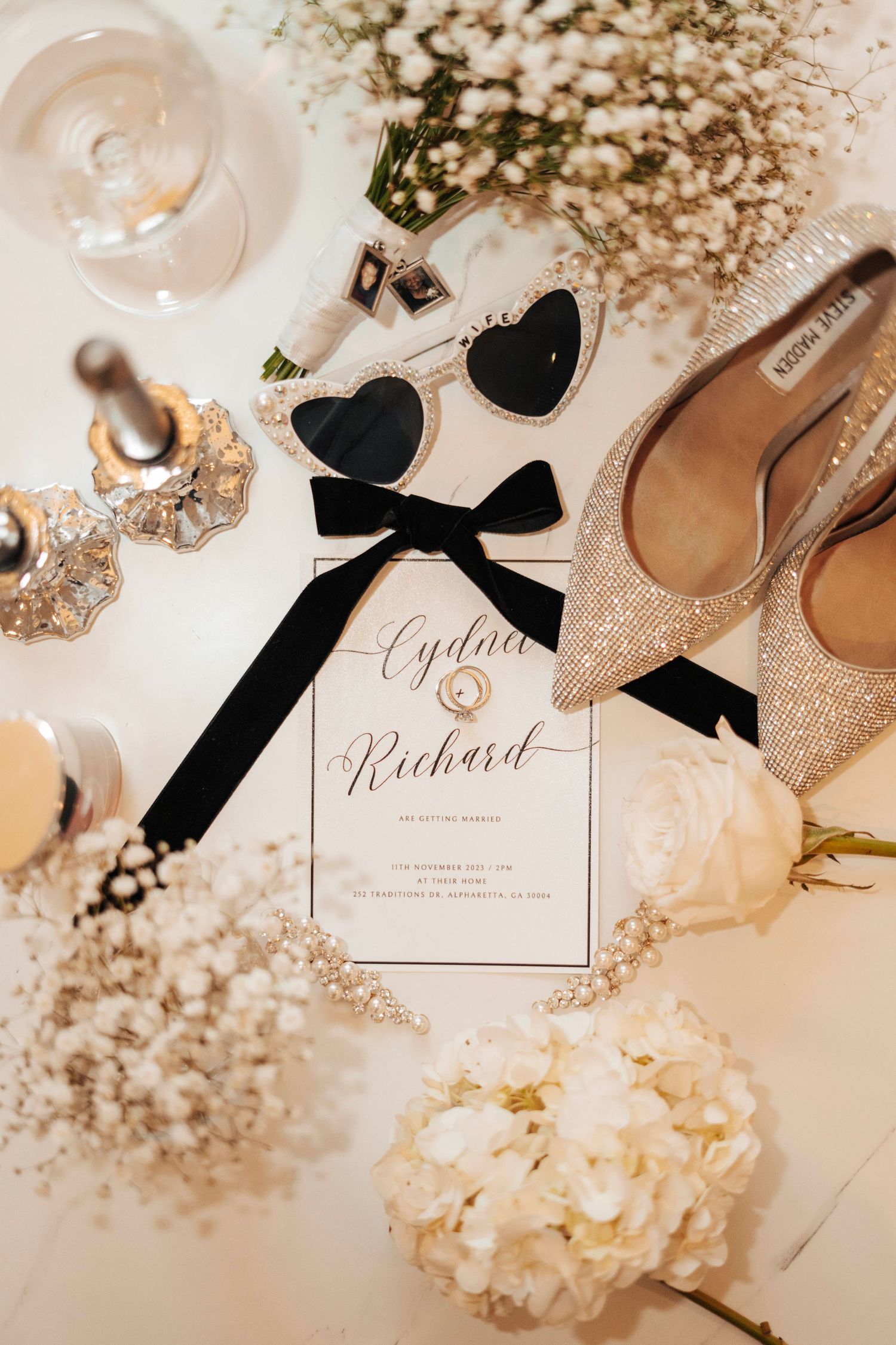 Wedding details flatlay with invitation, shoes, and delicate floral elements in soft beige tones.