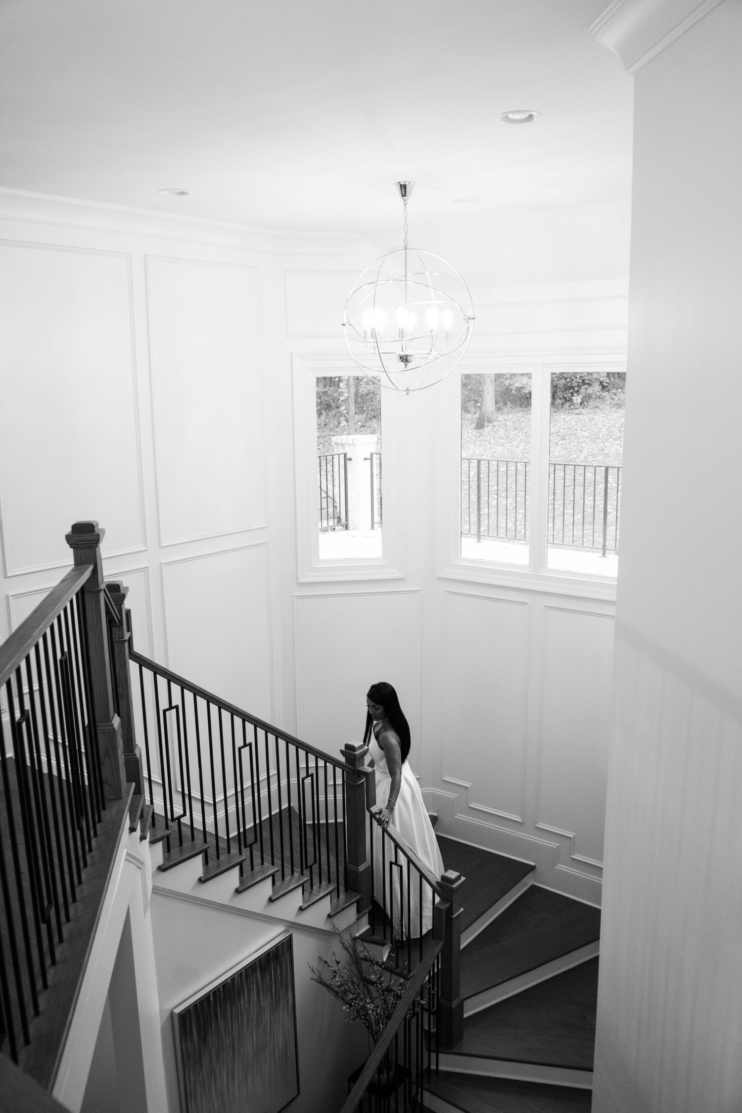 A person walks down a bright white interior staircase with black railings in a modern residential space.