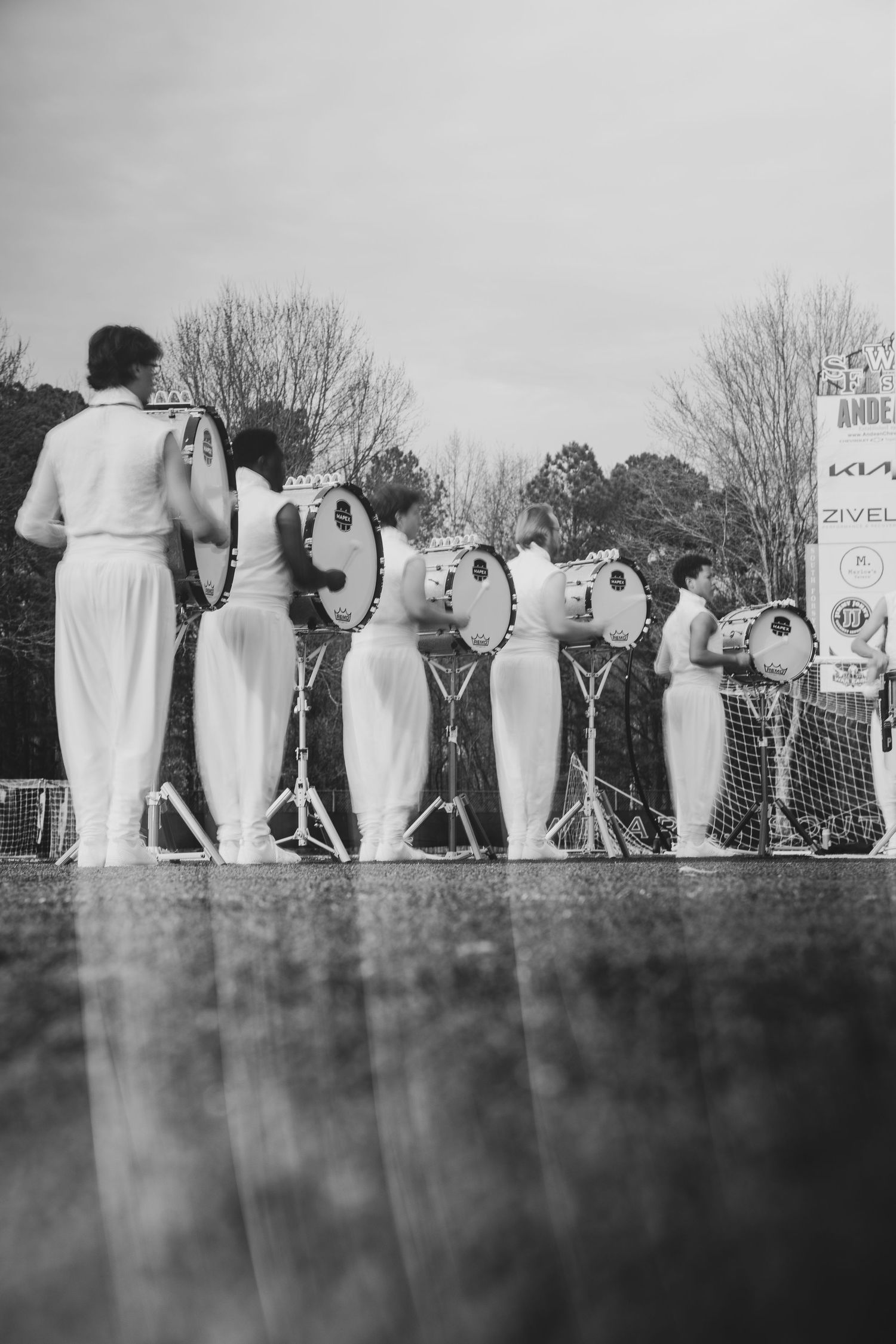 Black and white photo showing a line of wedding guests standing outdoors at a ceremony.