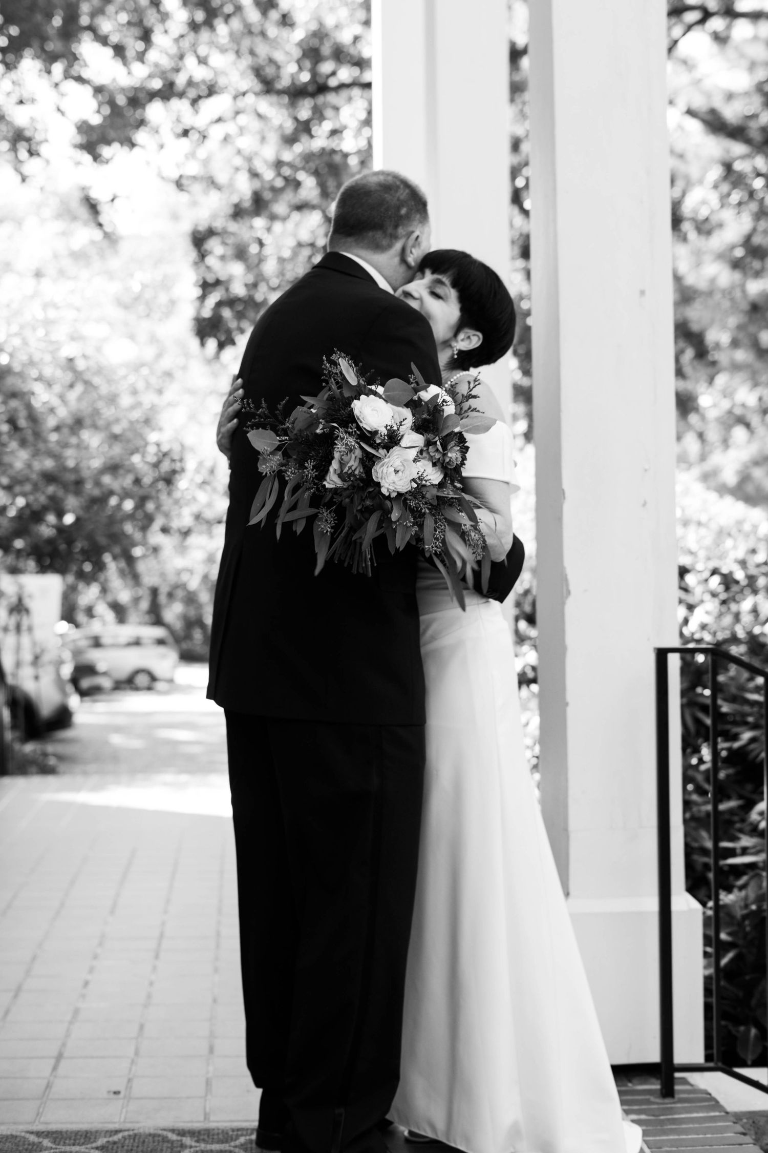 Couple shares first look moment under white columns with floral decorations.