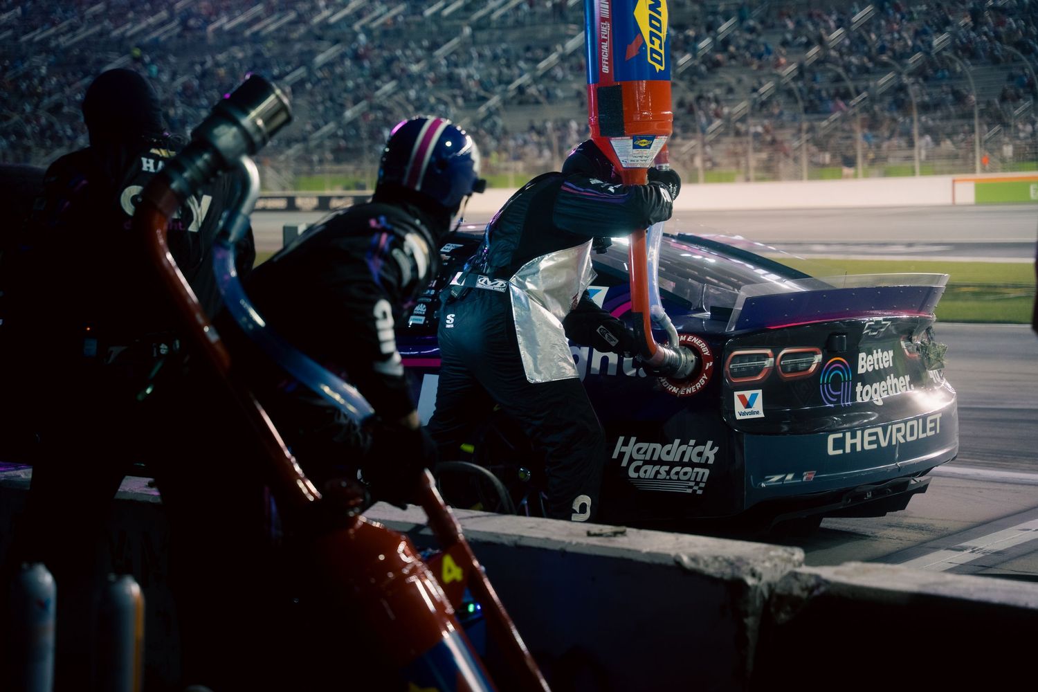 Racing cars battle for position on a professional racetrack during intense competition.