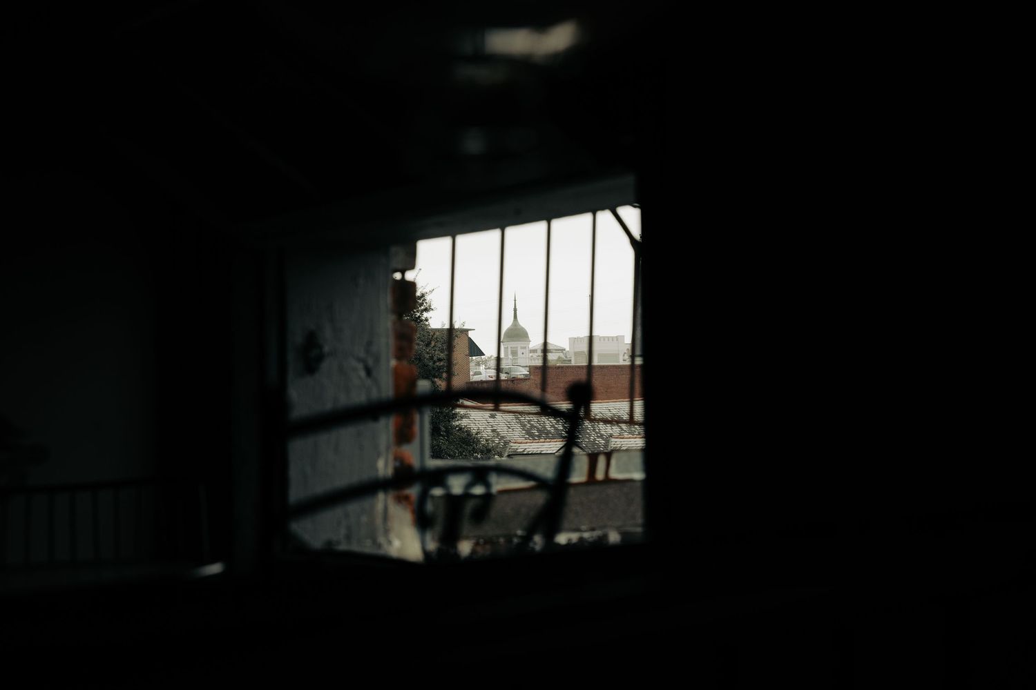 Dark interior space with light streaming through windows creating dramatic silhouettes.