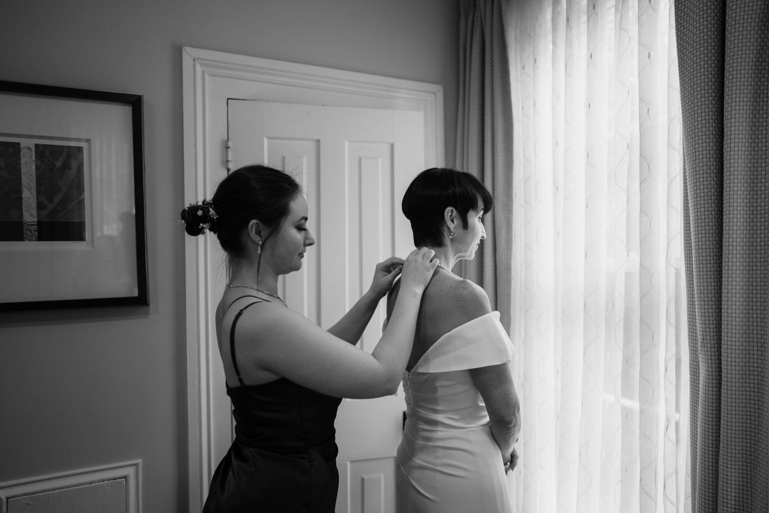 Wedding preparation moments captured in black and white through window light.