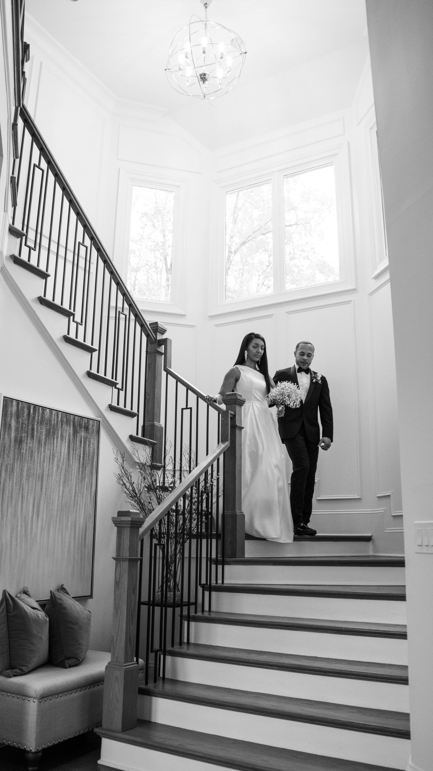 Elegant staircase with white walls and dark wood railings in a bright interior space.