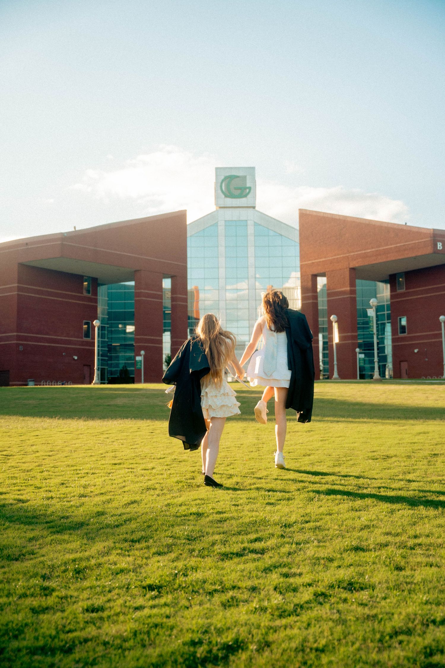 People standing on green lawn in front of modern brick and glass office building.