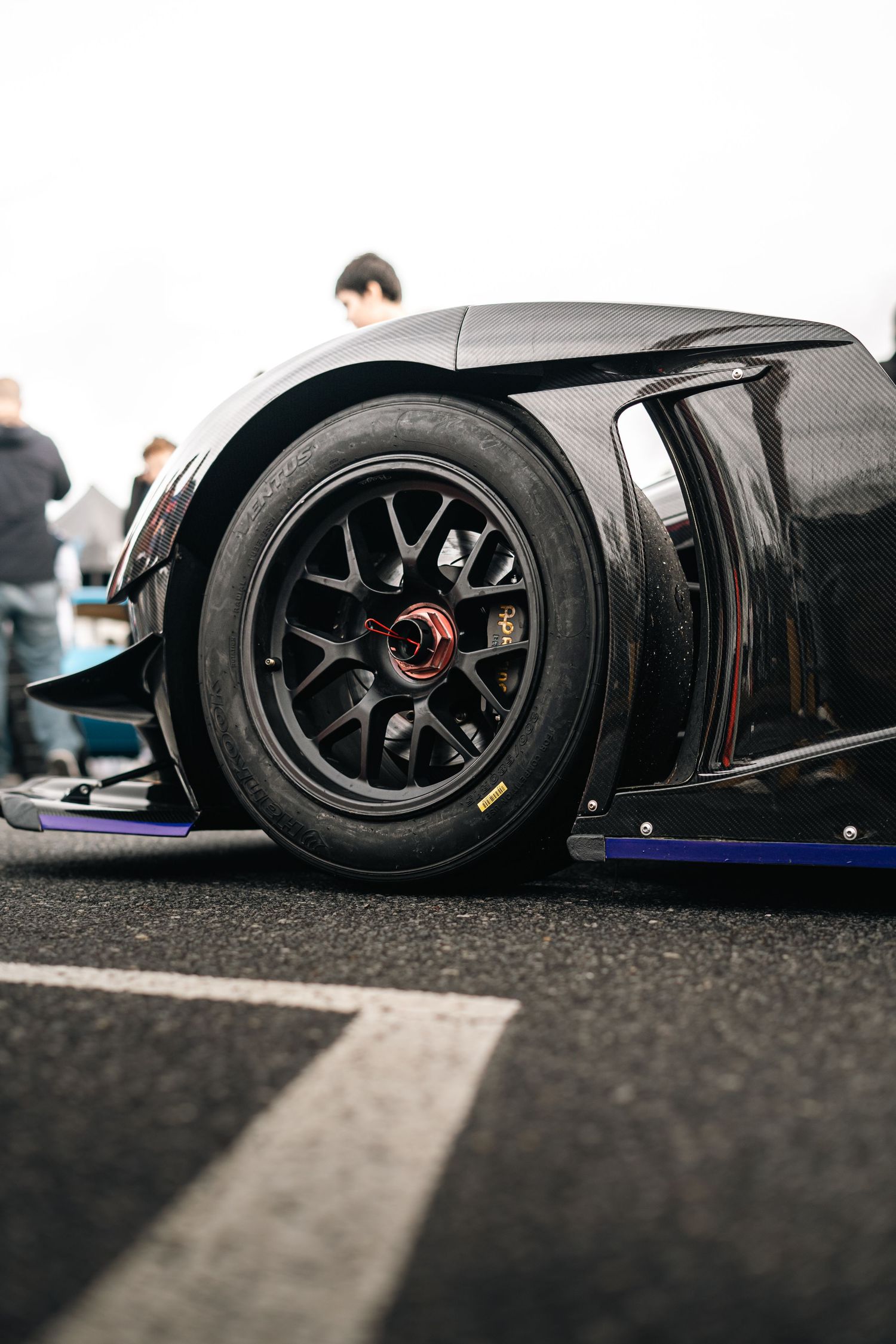 Low-angle view of black racing wheels and performance tires on a track-ready vehicle.