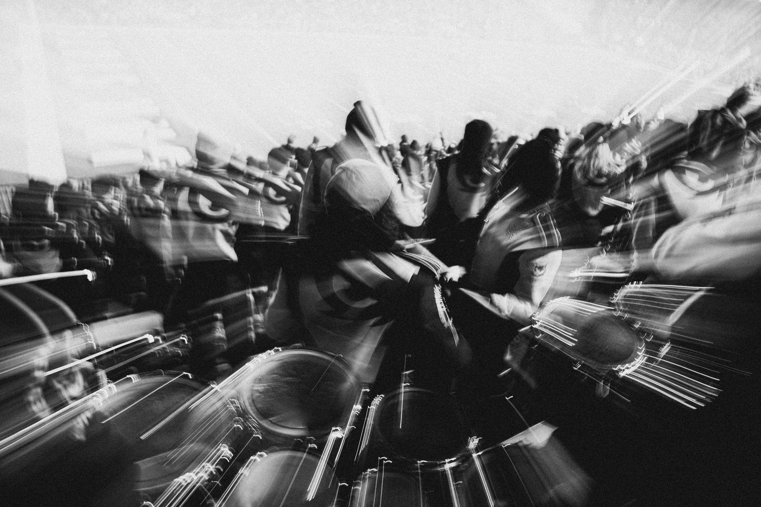 Black and white motion blur photo of a crowd in dynamic movement, creating an abstract swirling effect.