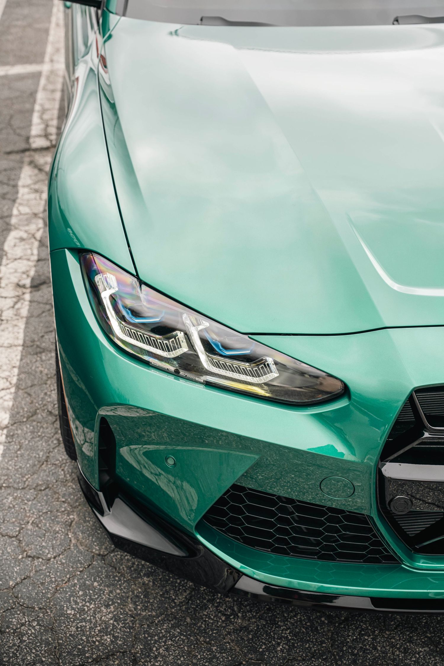 Mint green BMW M4's front end featuring modern LED headlights and signature kidney grille design.