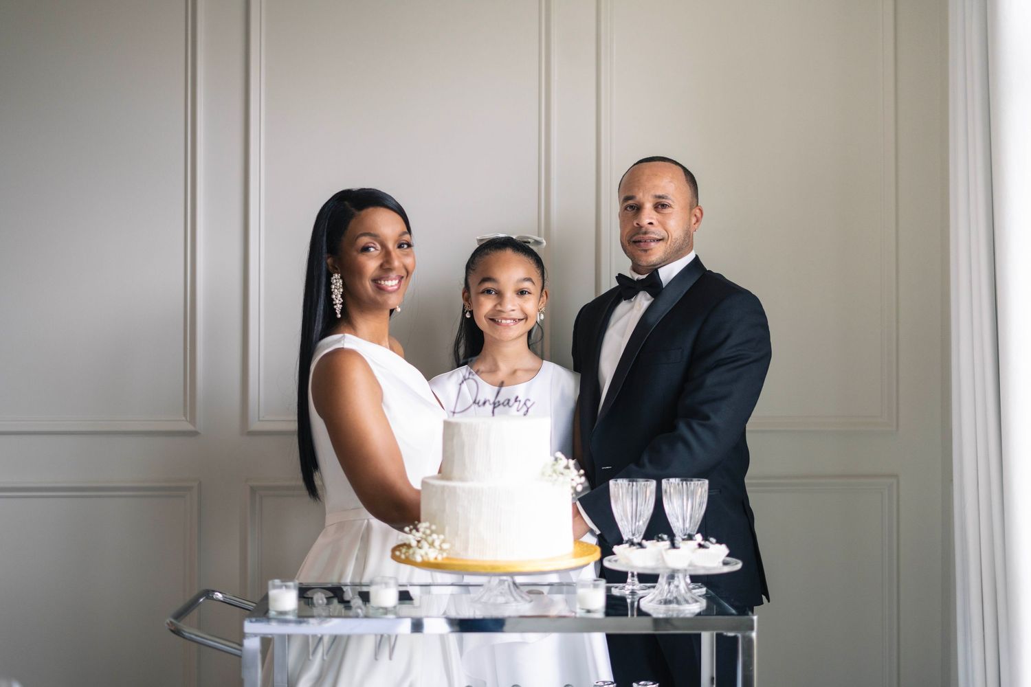 Wedding cake and champagne glasses displayed on elegant white table setting.