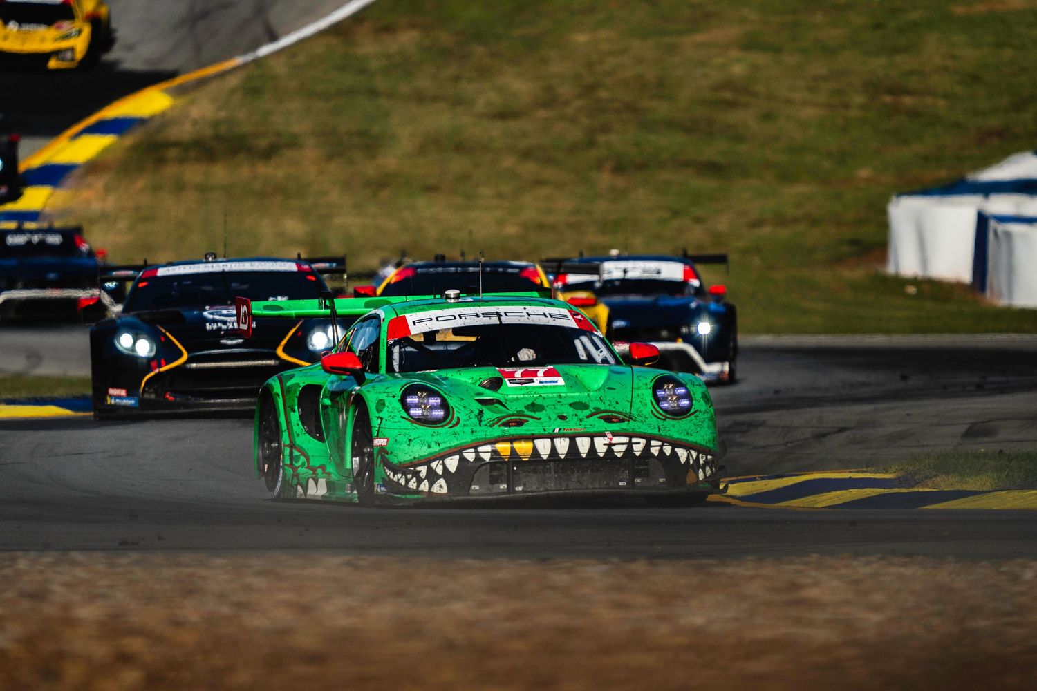 Multiple race cars compete on track with distinctive green livery visible.