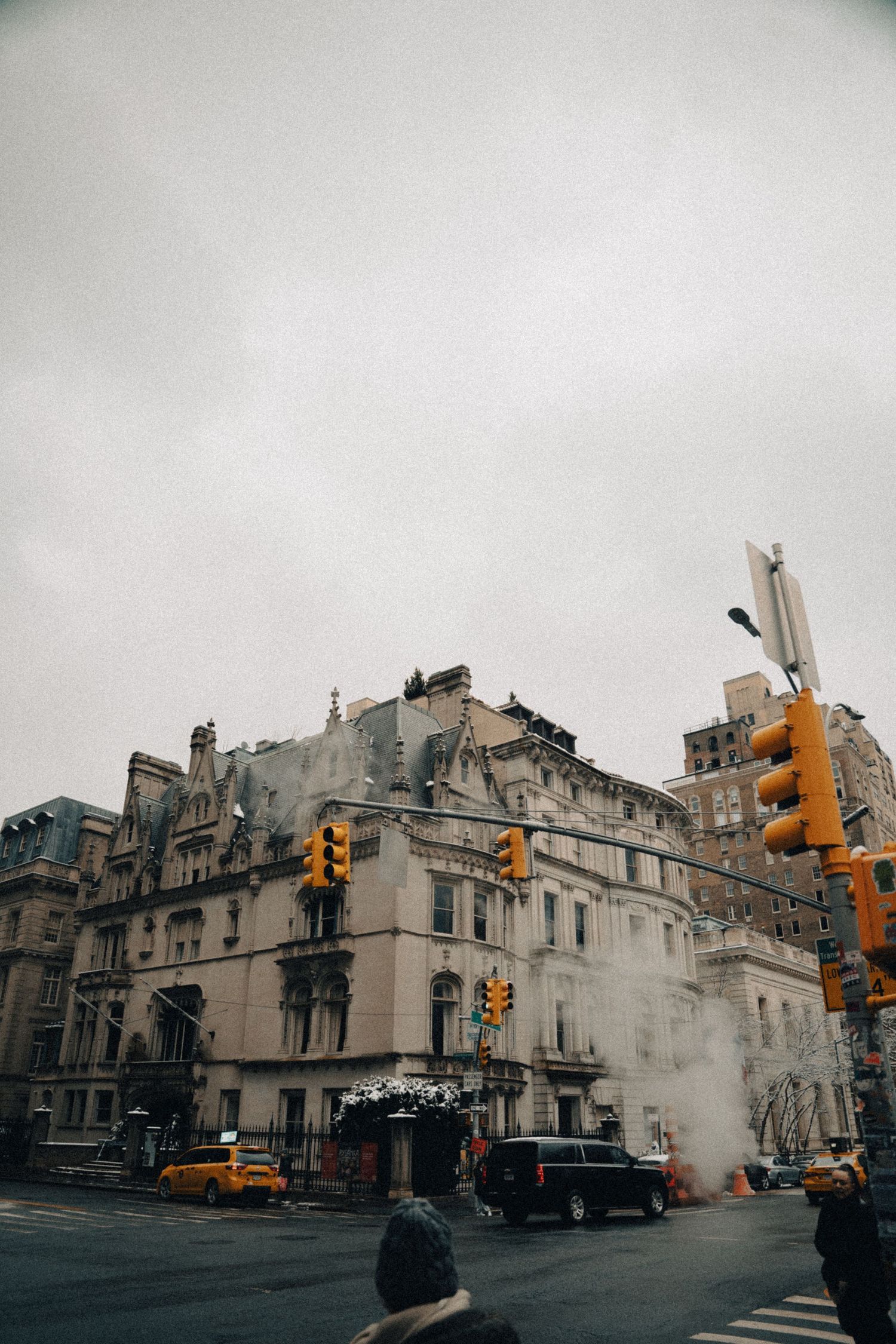 Moody urban street scene with historic buildings and yellow traffic lights in overcast weather.