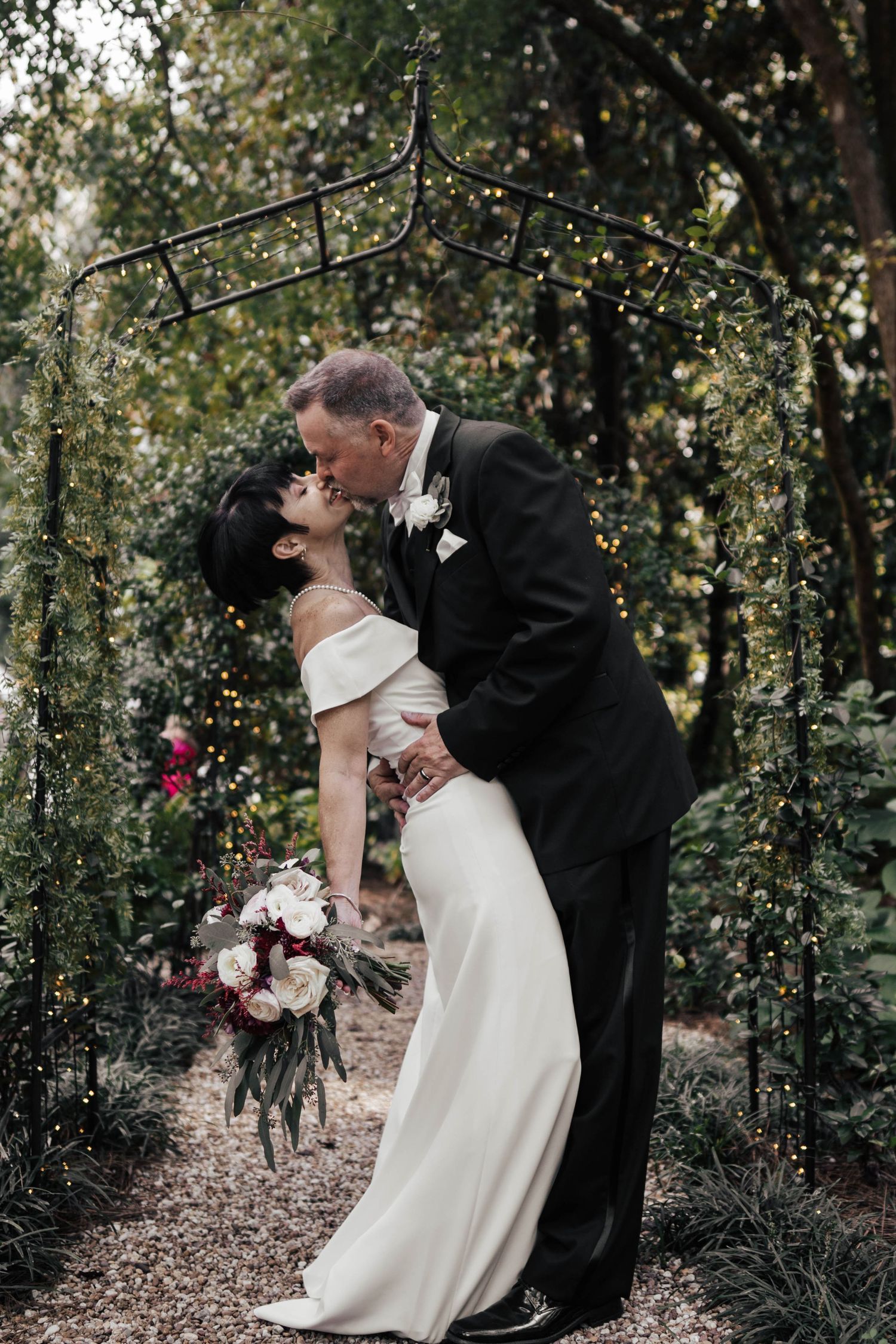 Romantic wedding couple posing in a lush garden setting with natural greenery.