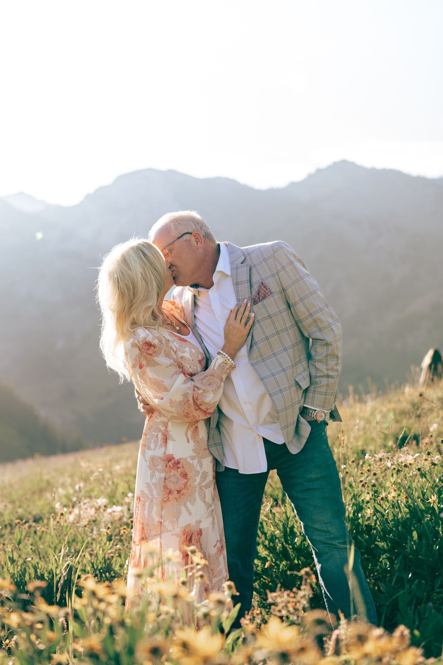 Romantic couple sharing intimate moment in mountain meadow at sunset.