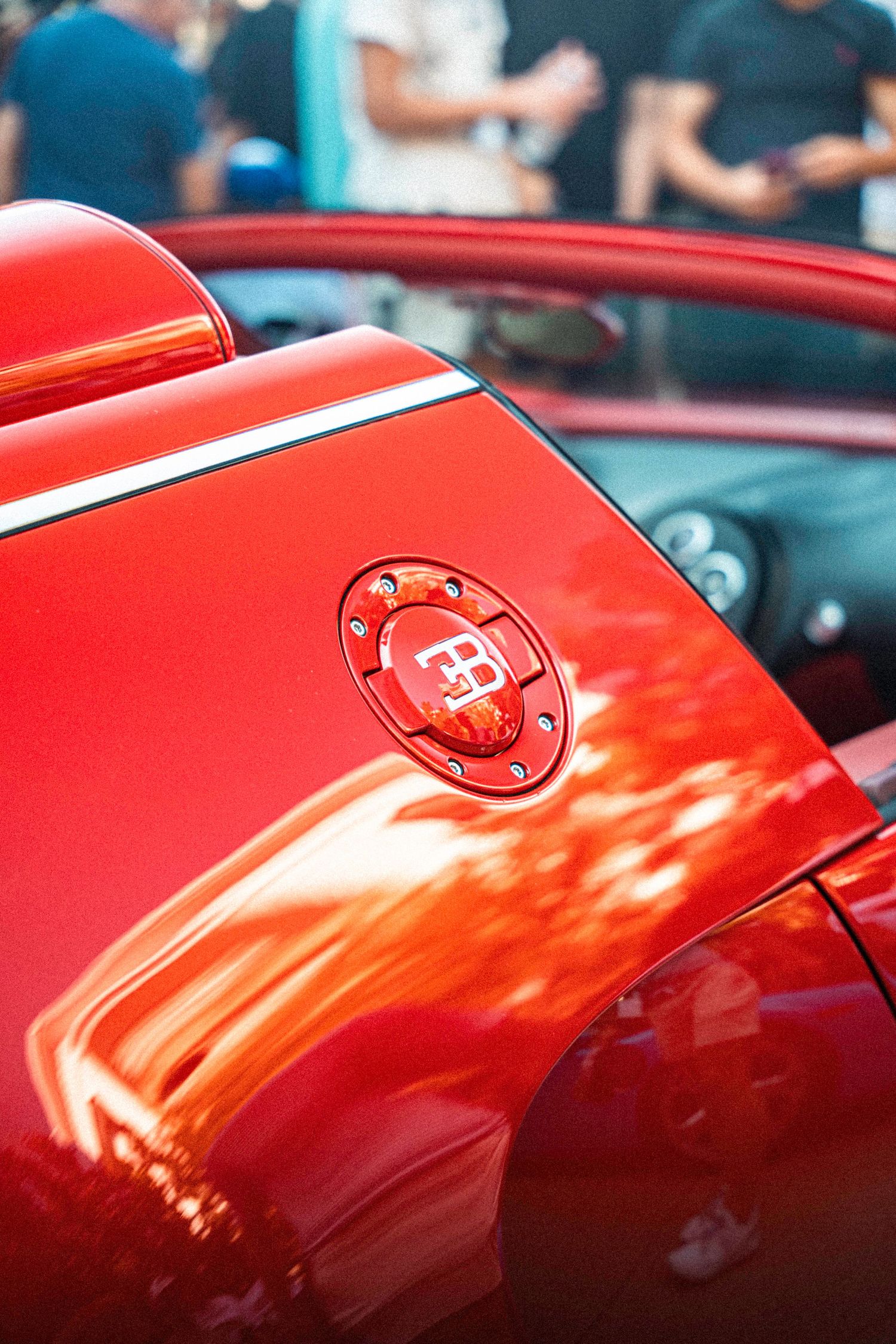 Red Bugatti supercar body panel with distinctive brand emblem detail.