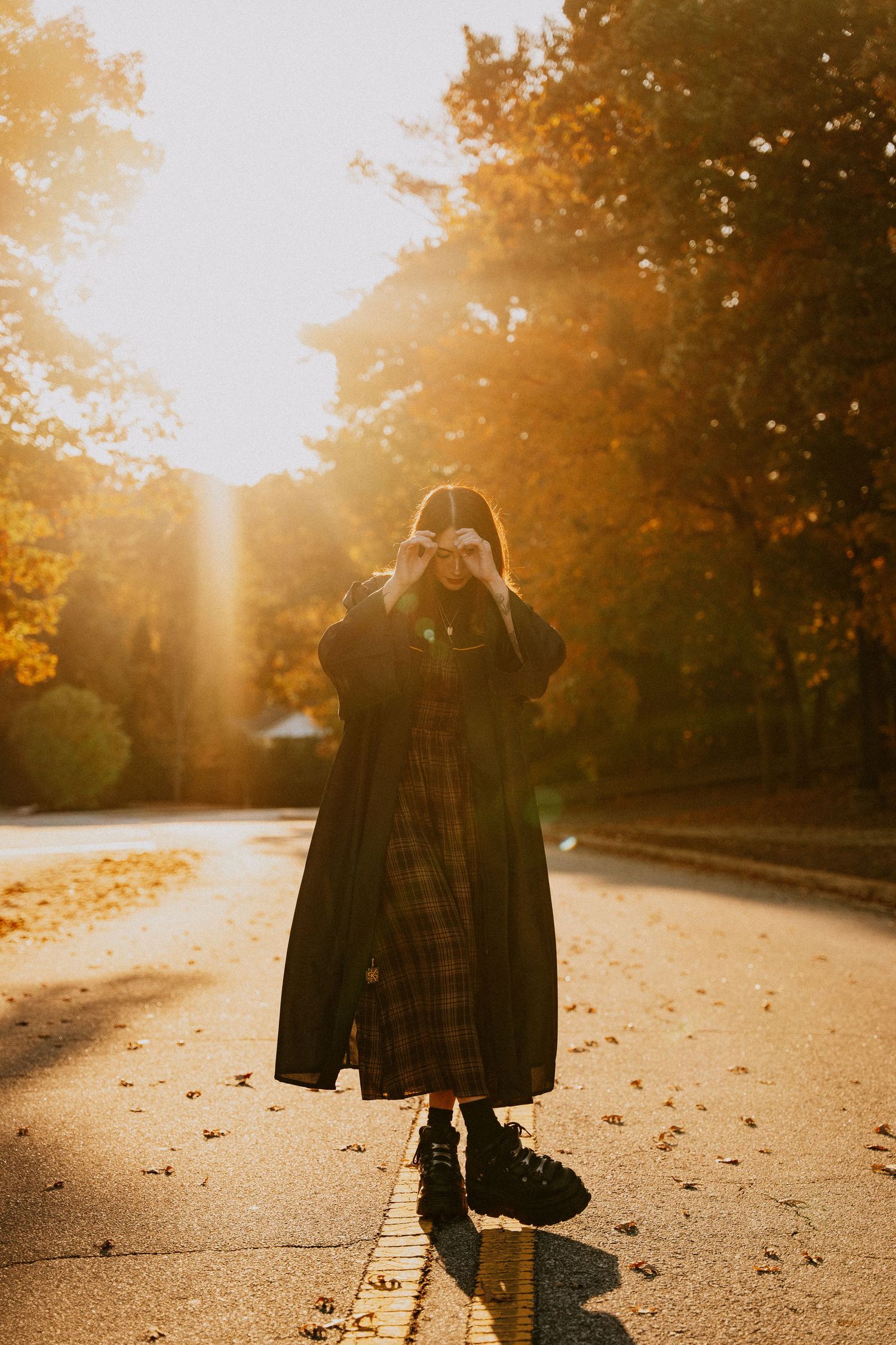 Silhouetted figure walking on autumn path with golden sunlight streaming through trees.