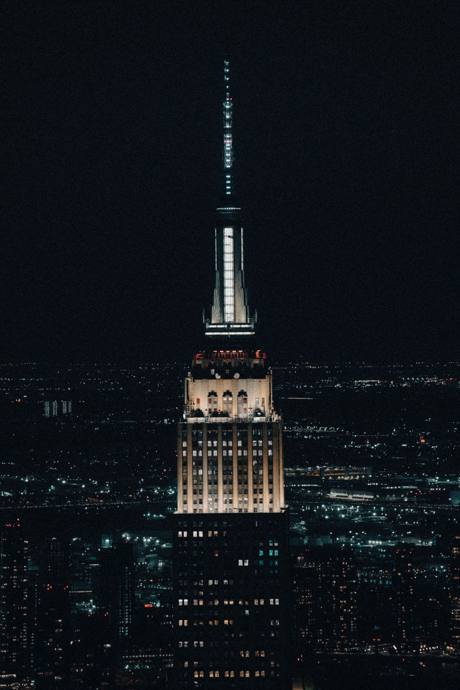 Art deco Empire State Building illuminated against the dark New York City skyline at night.