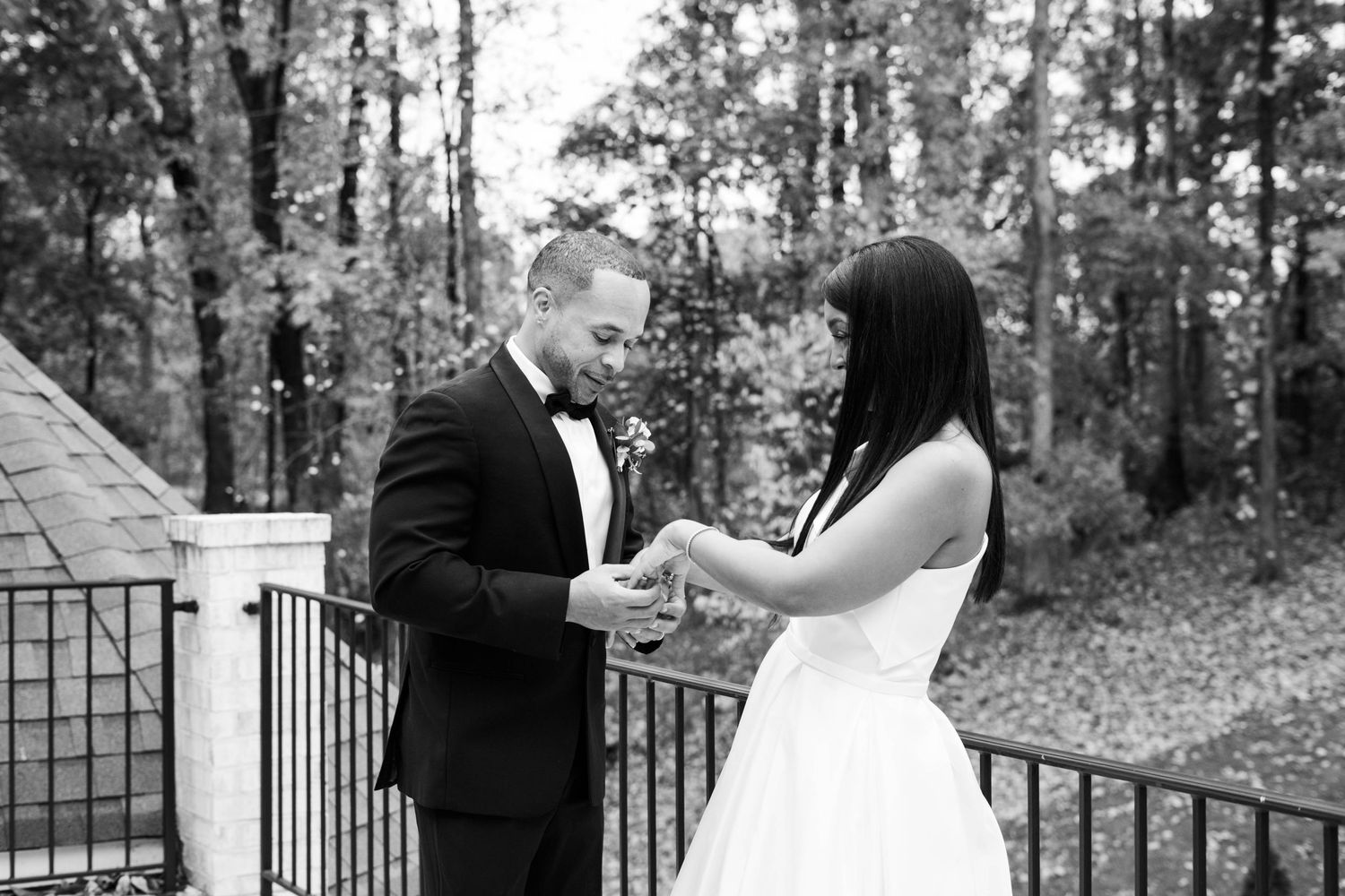 Romantic outdoor wedding portraits with couple embracing near iron railing and trees.