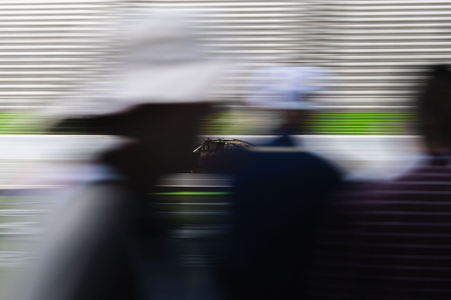 Blurred motion shot of racing action through track barriers during competition.