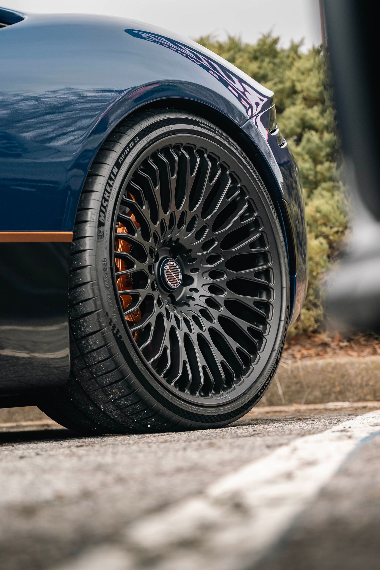 Black multi-spoke wheels with performance tires and red brake calipers on a luxury vehicle.