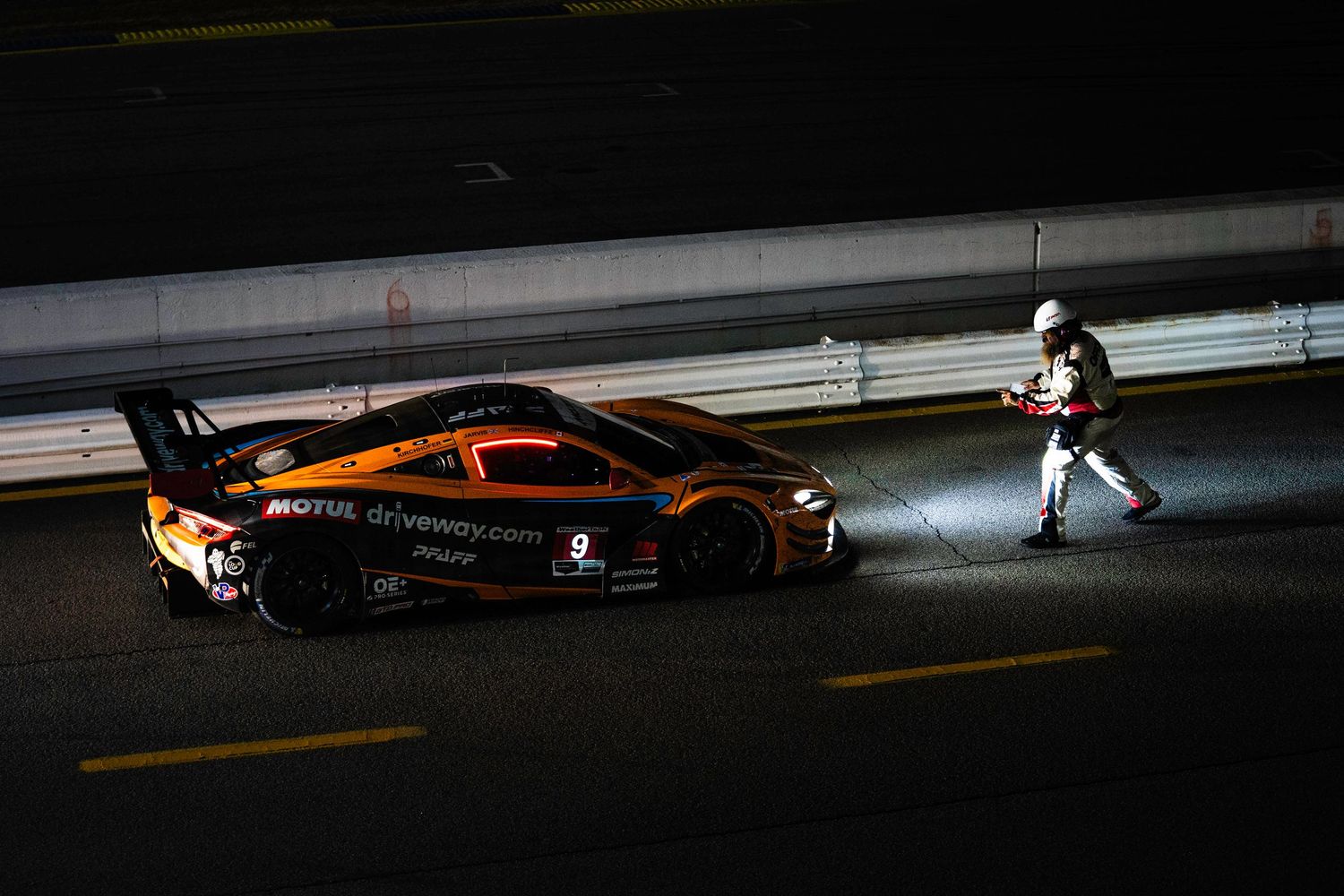 Race cars casting dramatic shadows on track during low-light conditions.