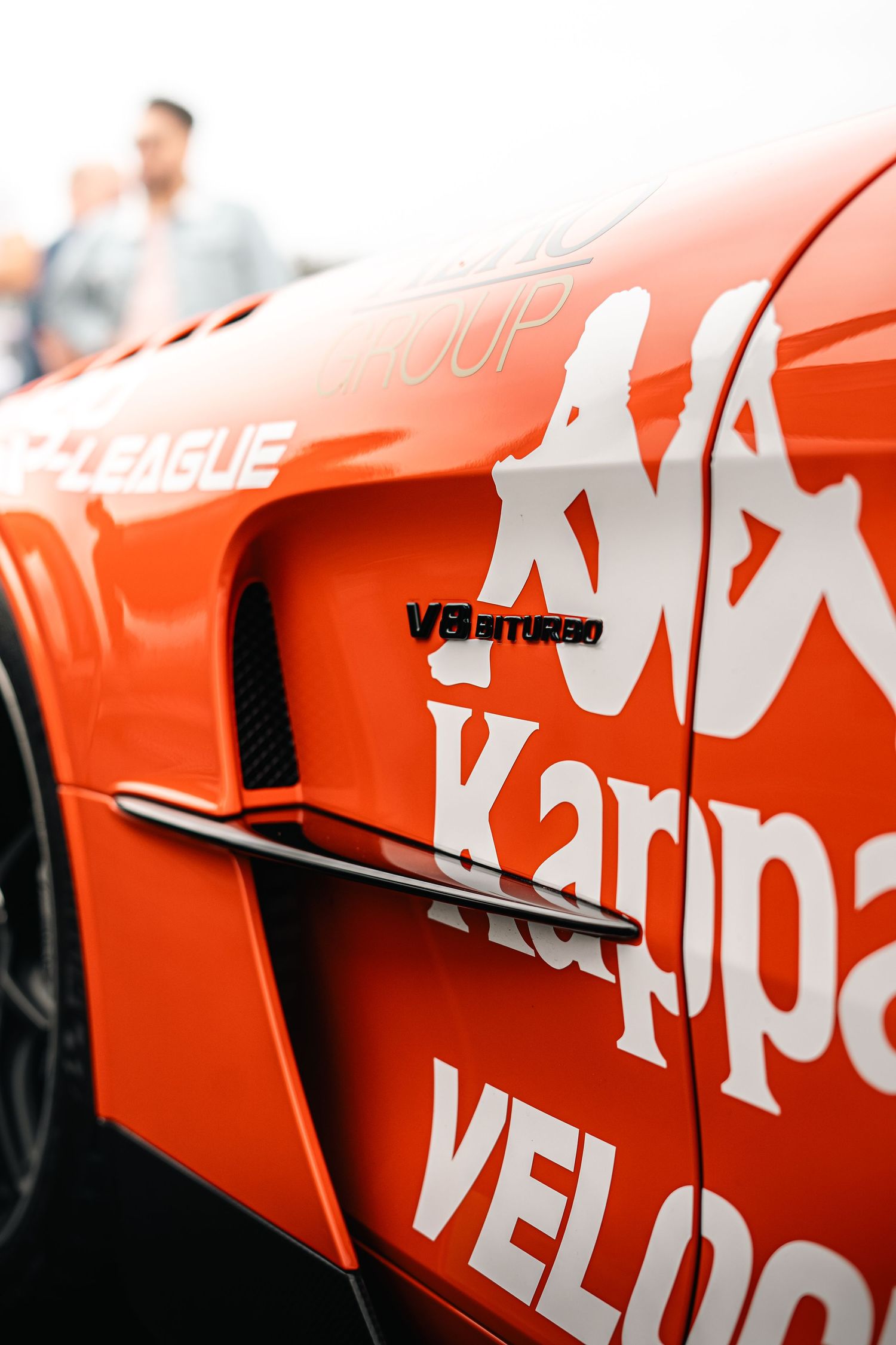 Orange racing car livery with white text graphics and sponsorship branding.
