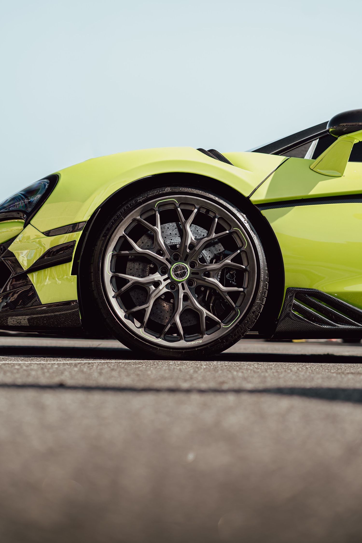 Close-up of neon yellow McLaren sports car wheel showing intricate rim design and brake caliper.