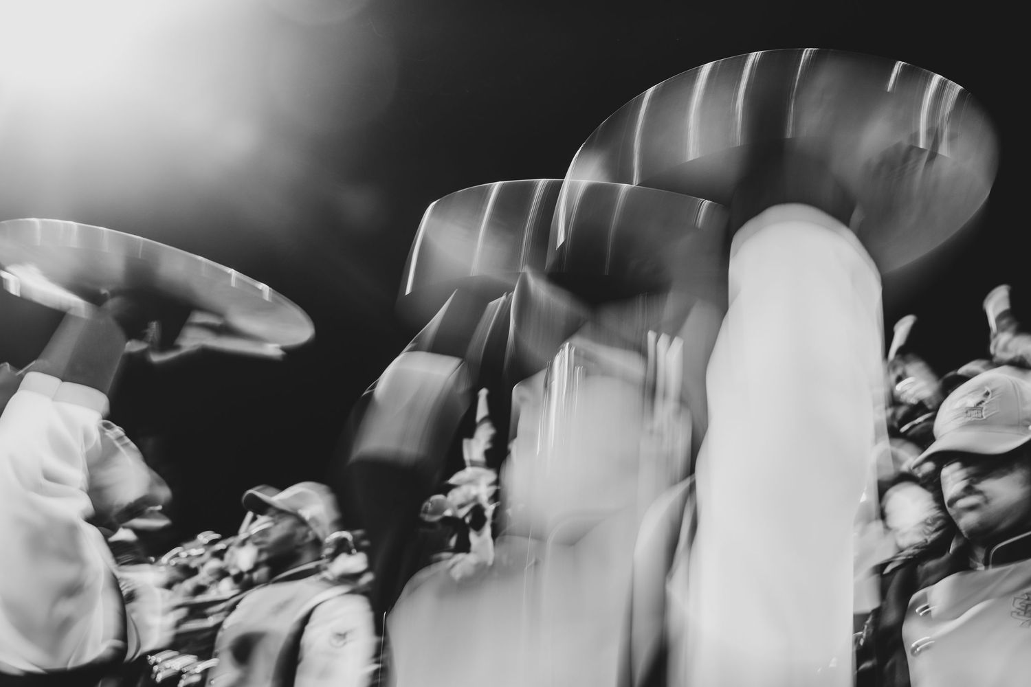 Motion-blurred black and white image of marching band members during performance.