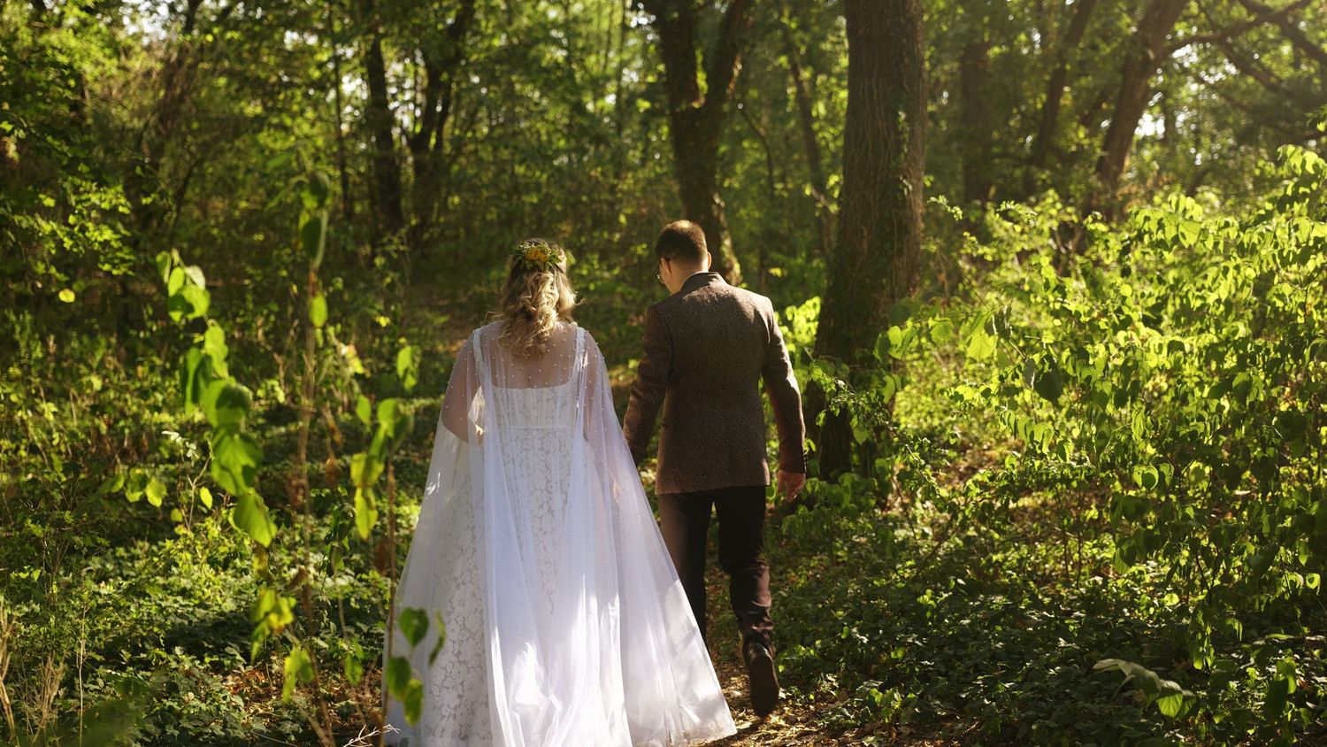 Sunlit garden path with lush greenery and trees creating a natural wedding ceremony setting.