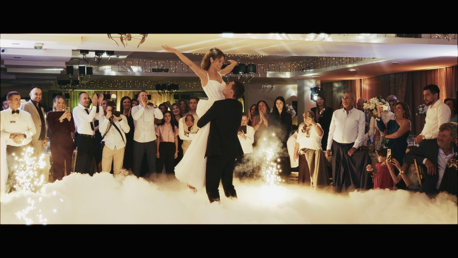 Wedding guests form a large circle on the dance floor during a reception celebration.