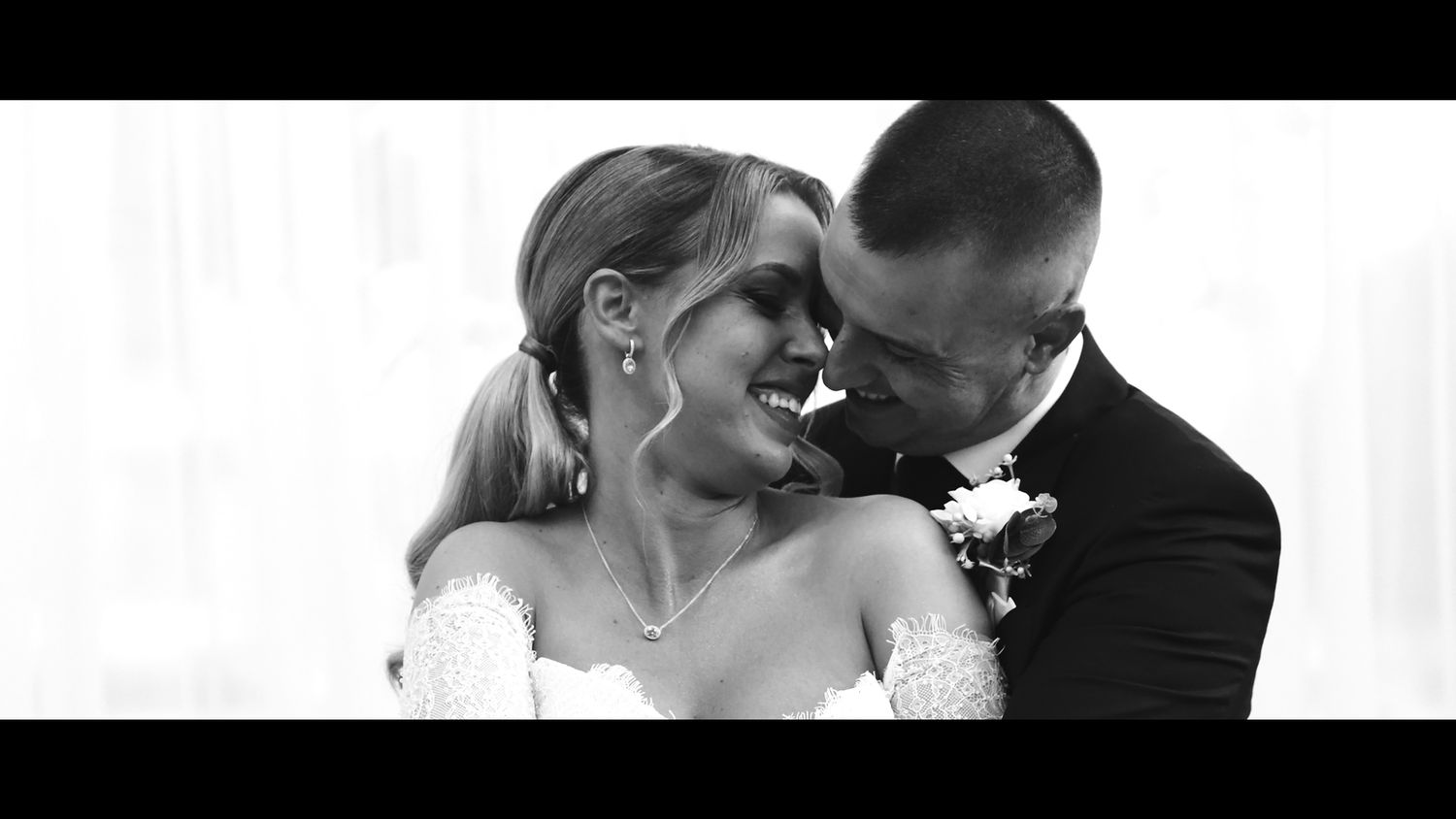 Intimate wedding moment captured between couple under white drapery.