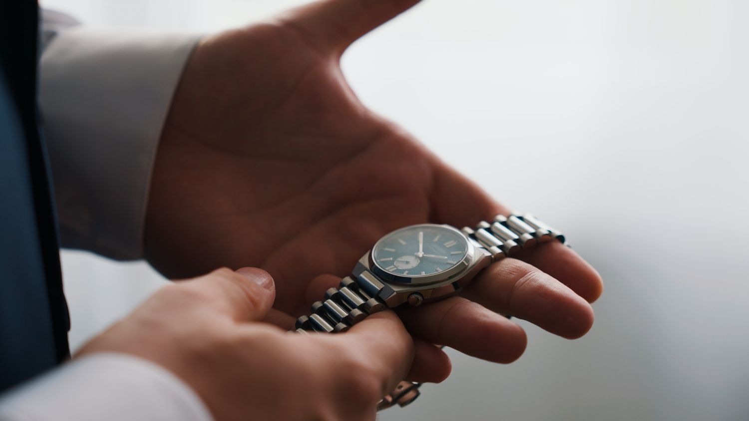 Detail shot of hands adjusting a watch on a formal occasion.