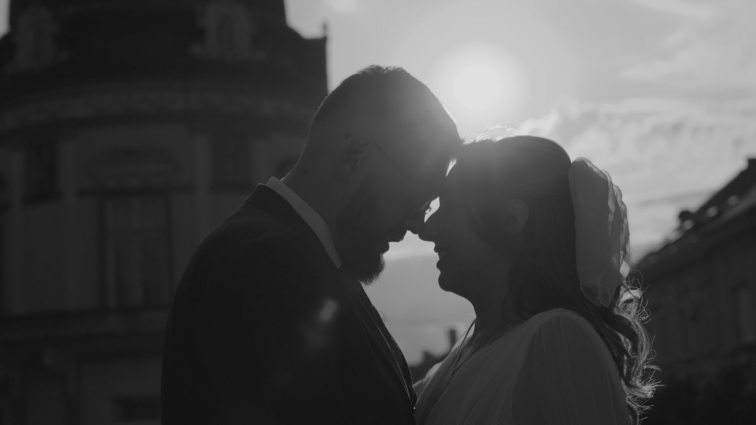 Black and white silhouette of wedding couple against dramatic sky.