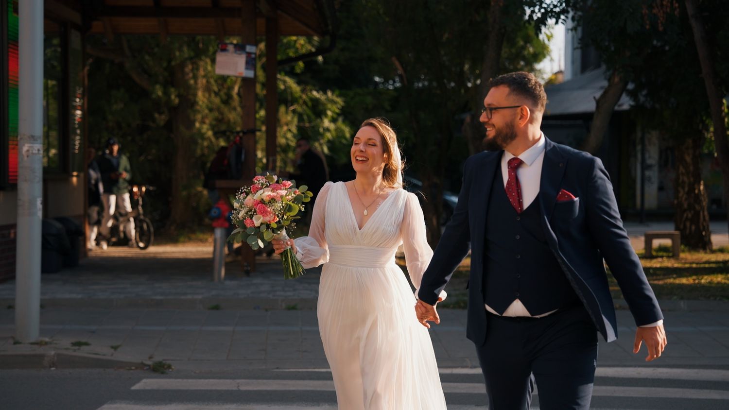 Wedding party walking along a tree-lined path in formal attire.