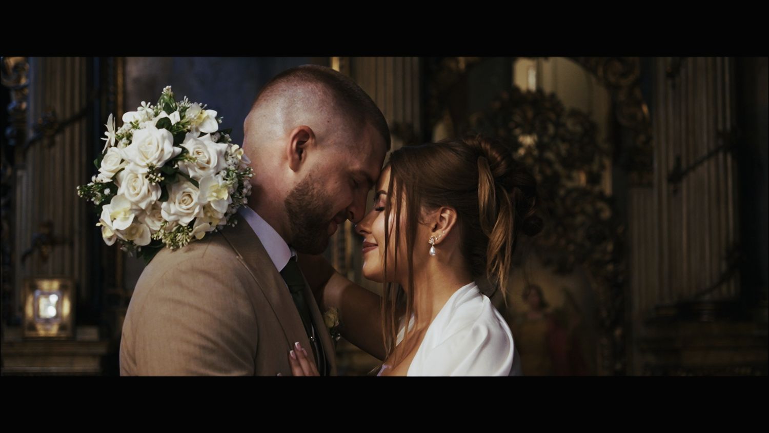Elegant wedding couple sharing romantic moment among decorative columns.