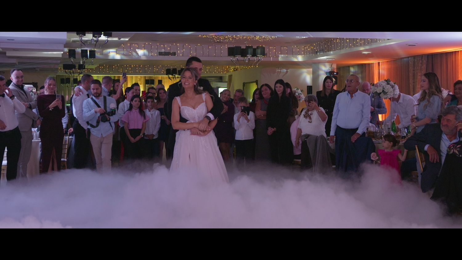 Wedding reception guests dancing and celebrating on a lively dance floor with colorful lighting.