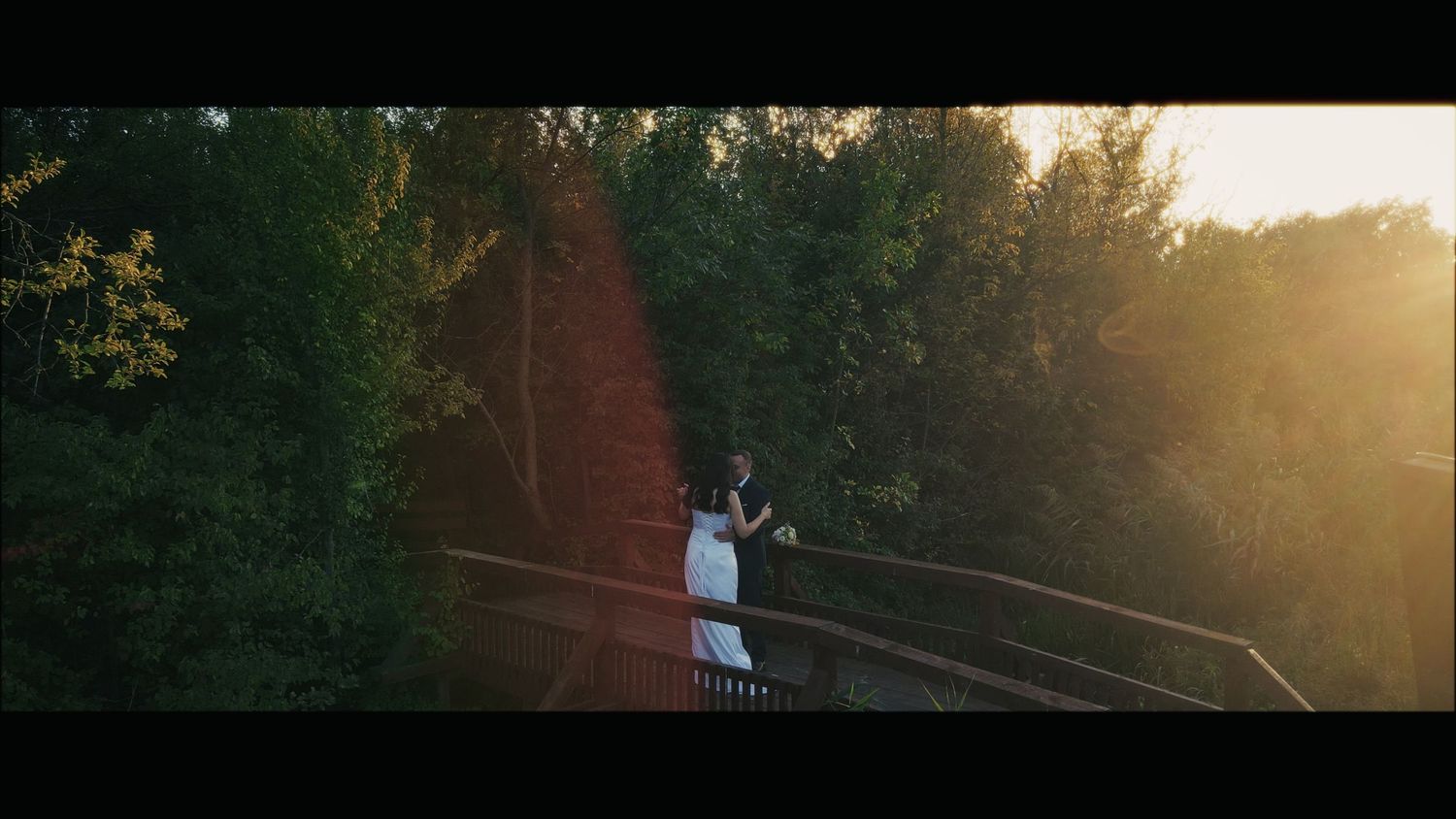 Golden sunset through trees creating a warm glow over an outdoor wedding venue.