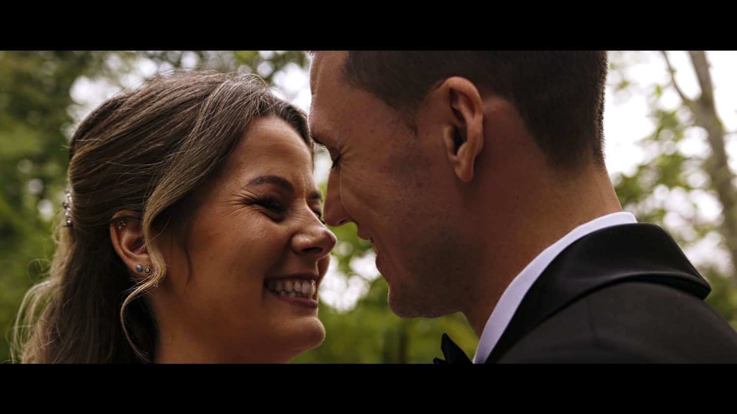 Close up of couple gazing at each other outdoors in wedding attire.