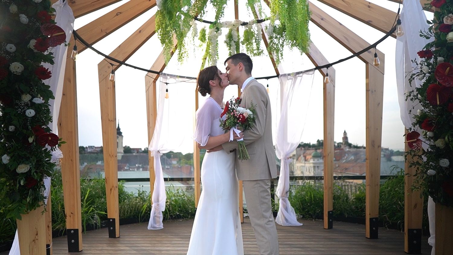 Wedding ceremony setup under a wooden gazebo decorated with flowers and greenery.