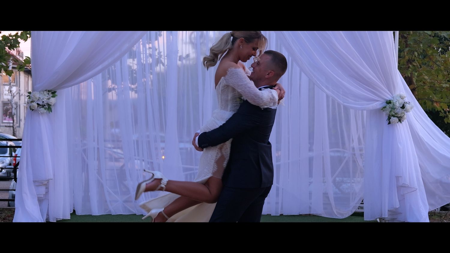Couple sharing a romantic dance moment under white flowing drapery at their wedding reception.