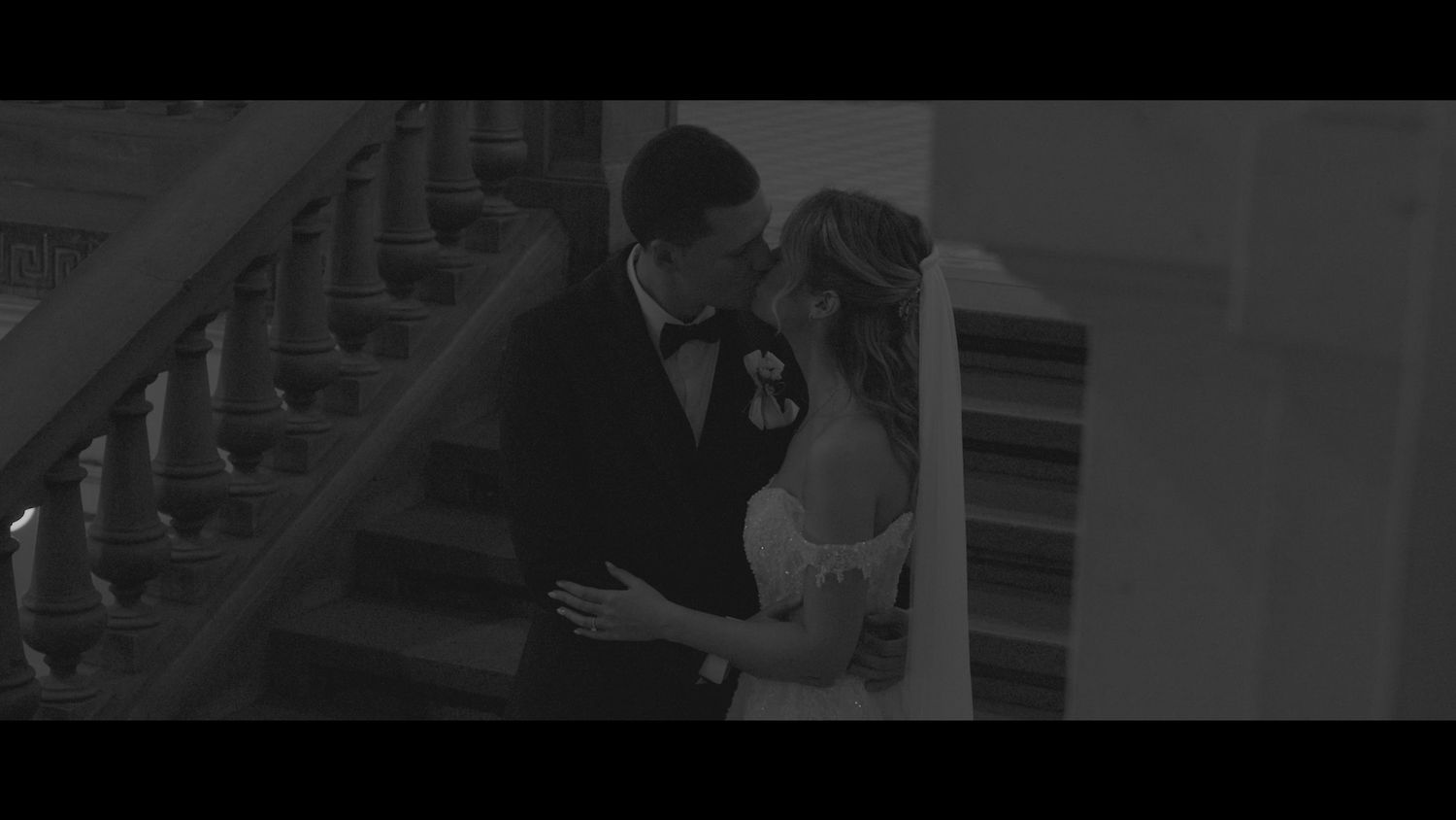 Black and white photo of couple sharing romantic moment on grand staircase.