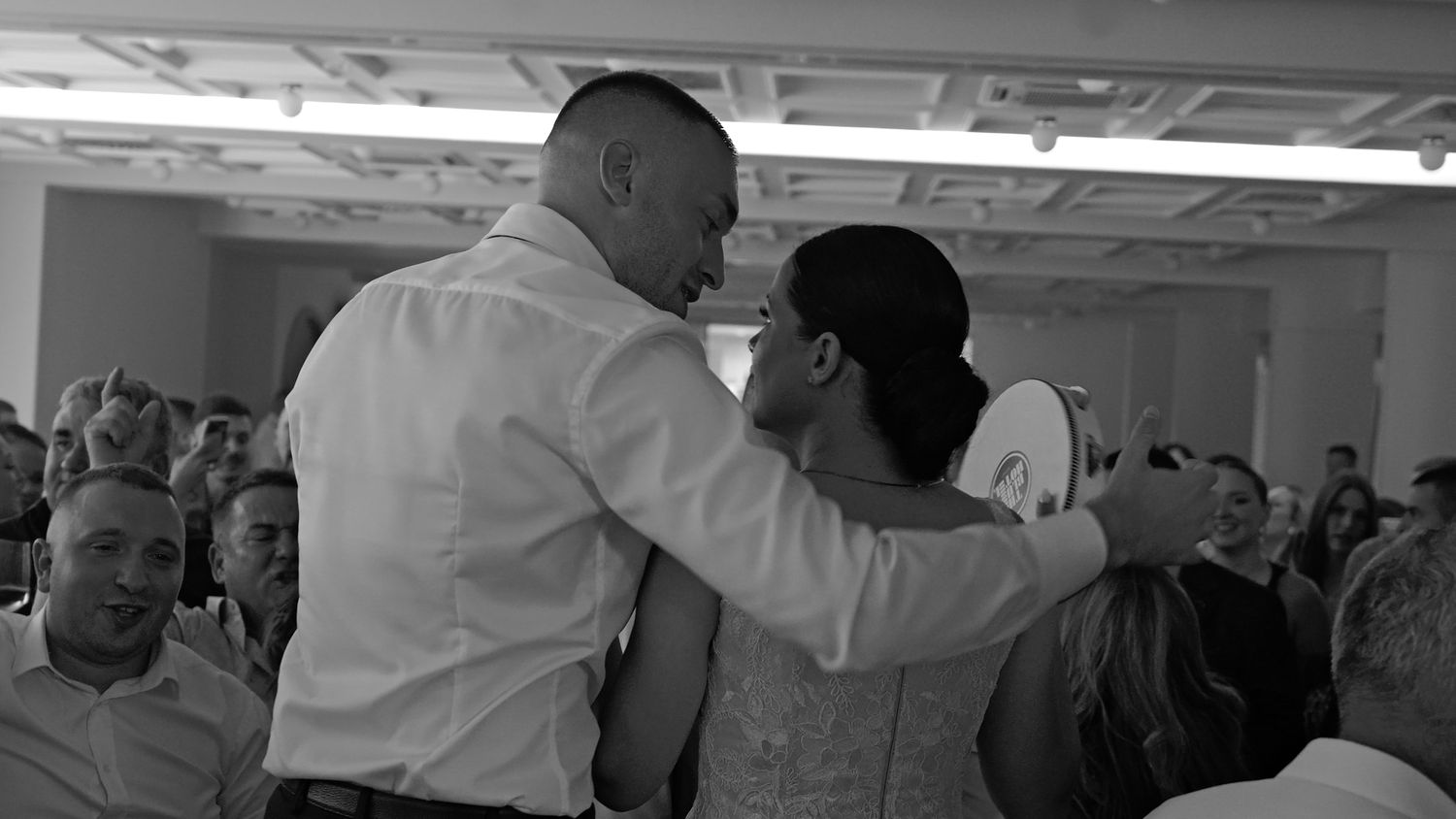 Wedding reception guests dancing and celebrating in indoor venue.
