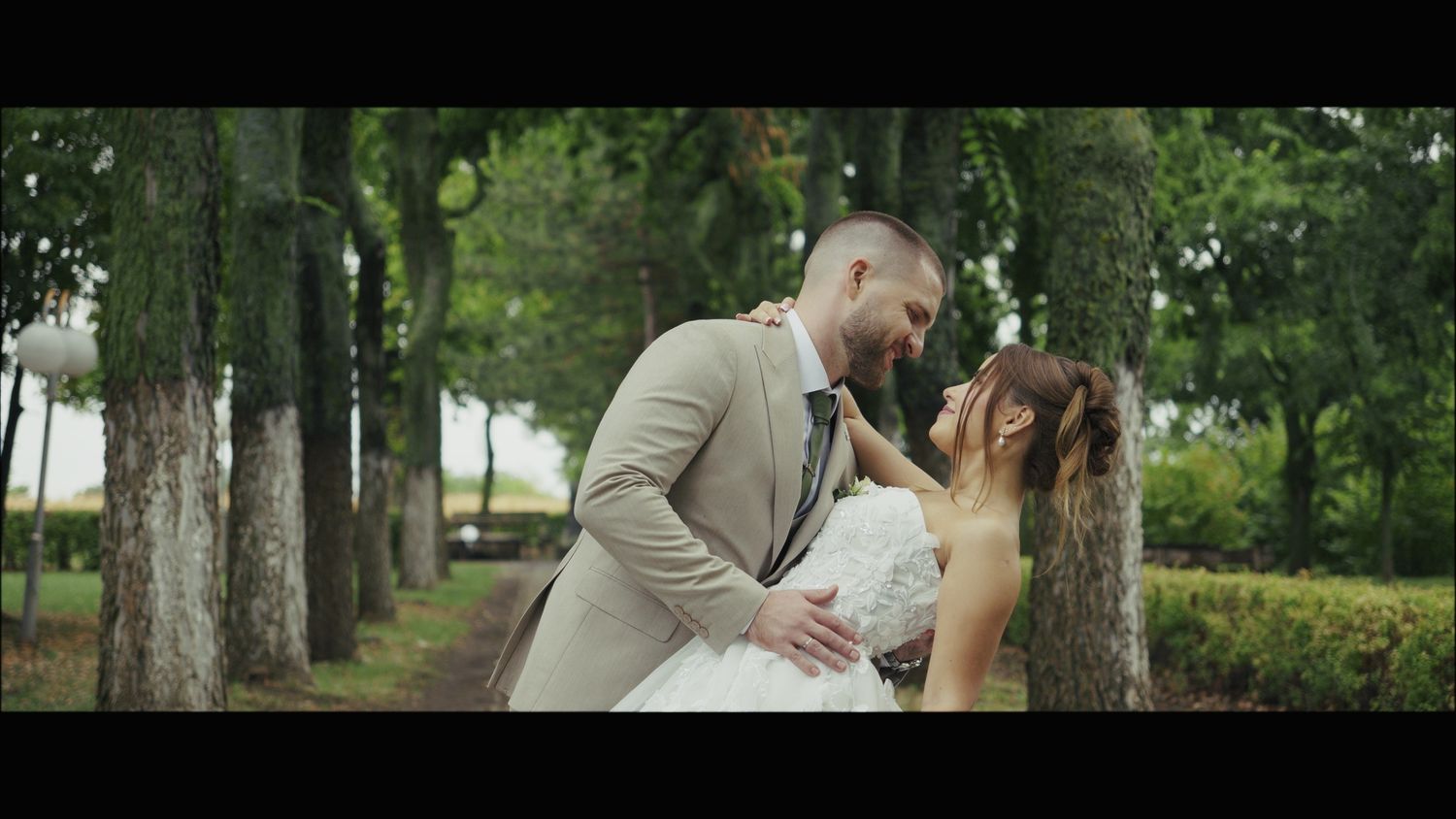 Romantic outdoor wedding moment captured between couple in a wooded park setting.