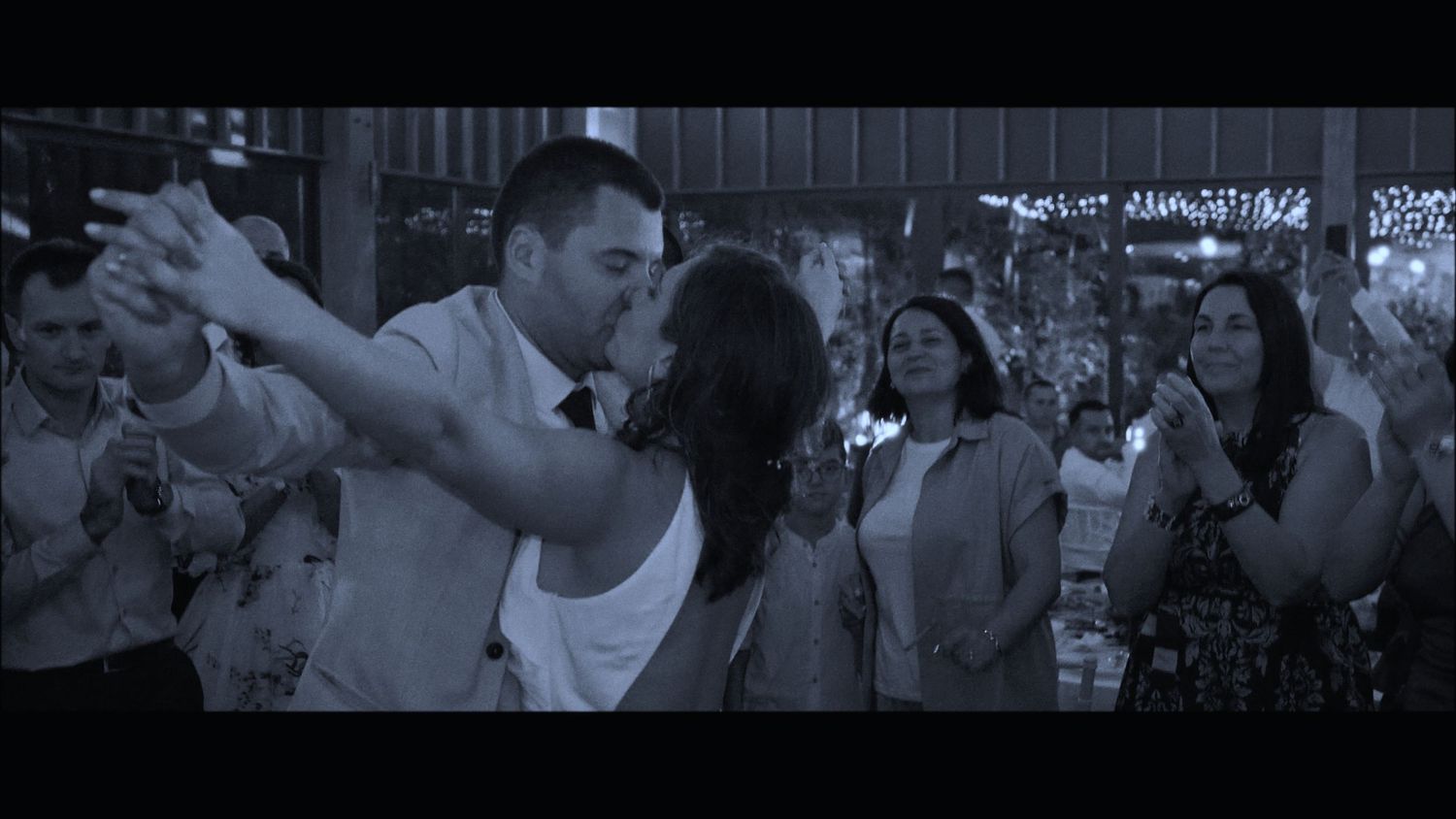 A couple dancing together at a wedding reception surrounded by guests.