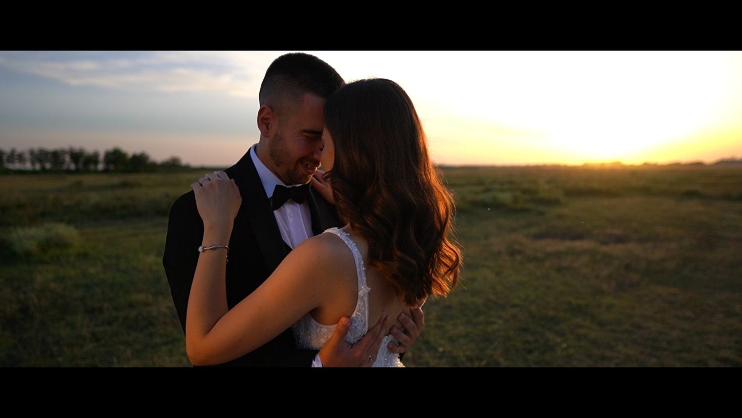Romantic sunset portrait of newlyweds in a golden field.
