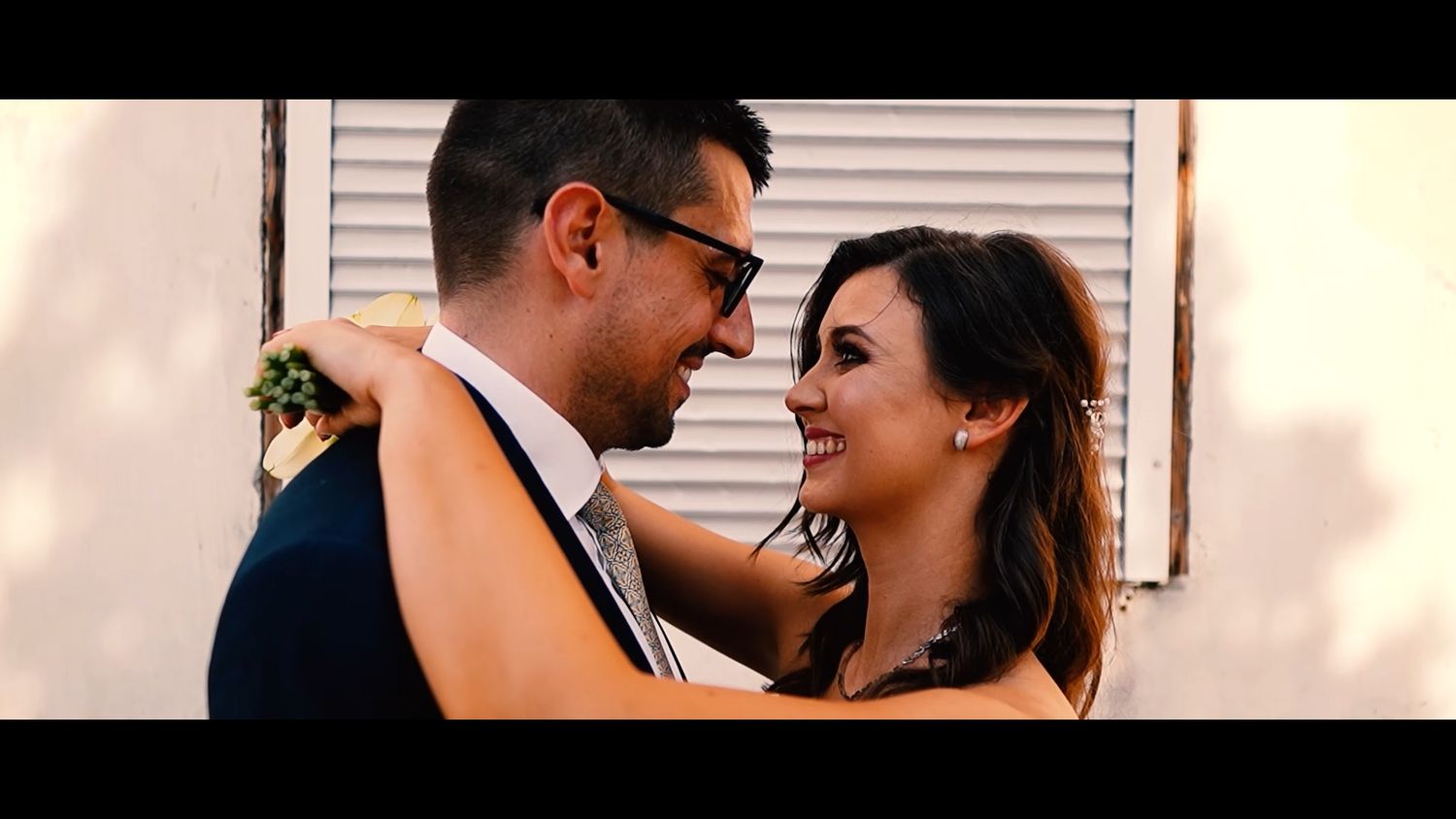 Intimate wedding couple portrait against a light colored wall.