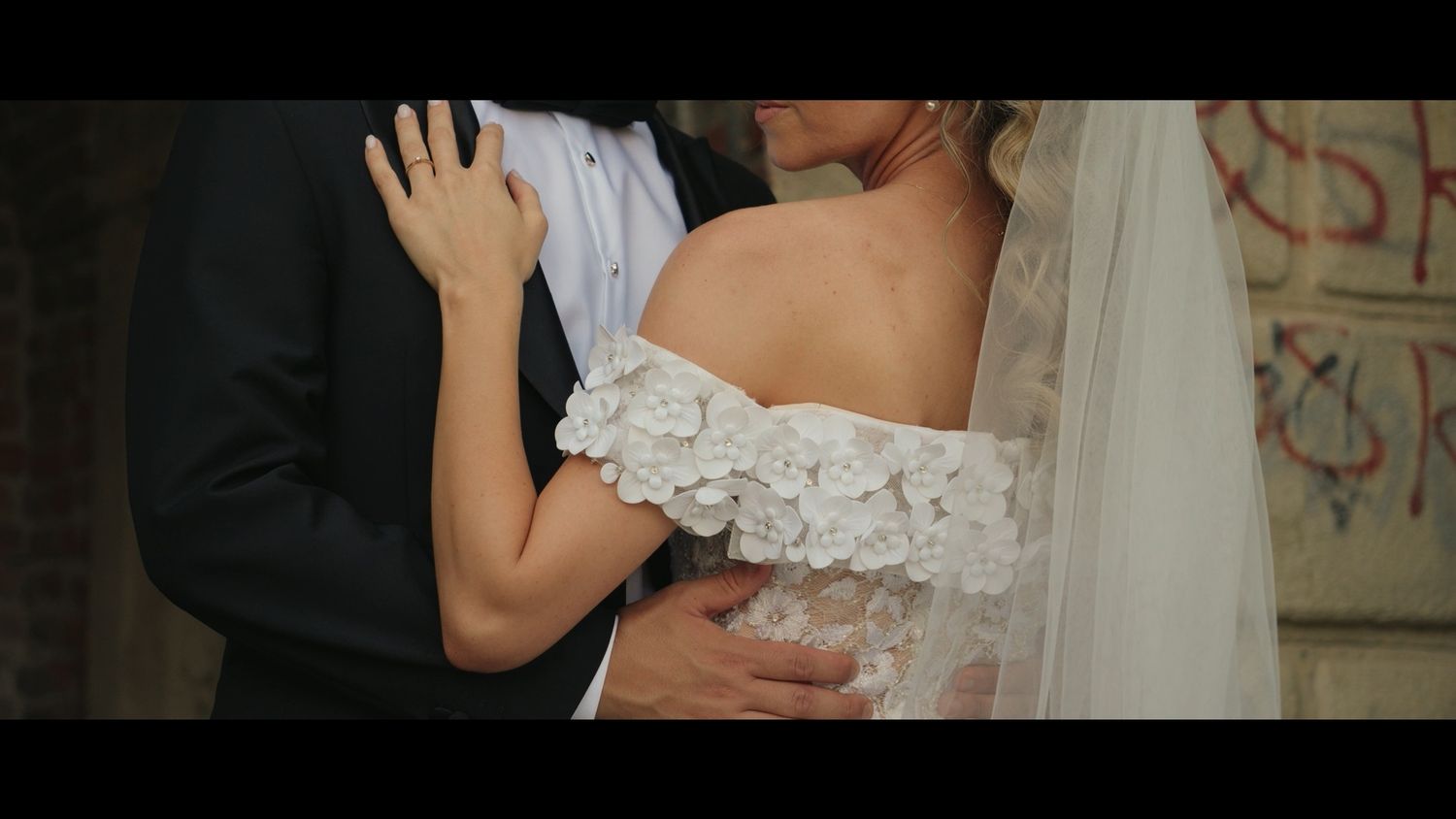 Close-up of wedding couple's embrace showing detailed lace dress.
